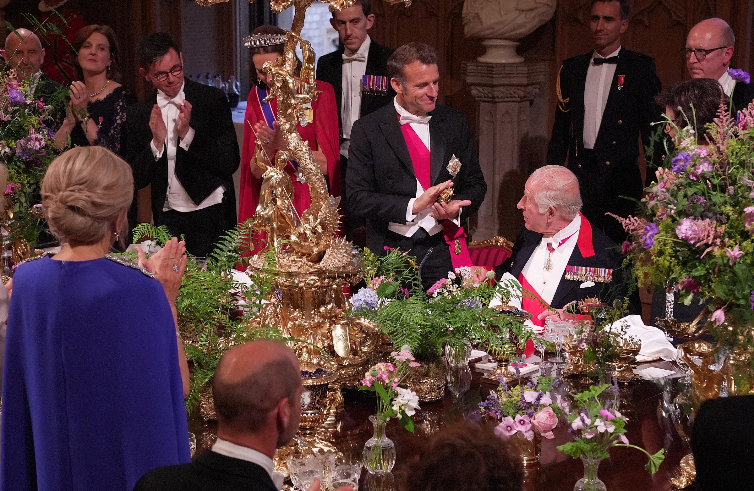 President Emmanuel Macron applauds after Britain's King Charles III delivered a speech during a State Banquet at Windsor Castle on the first day of his visit.