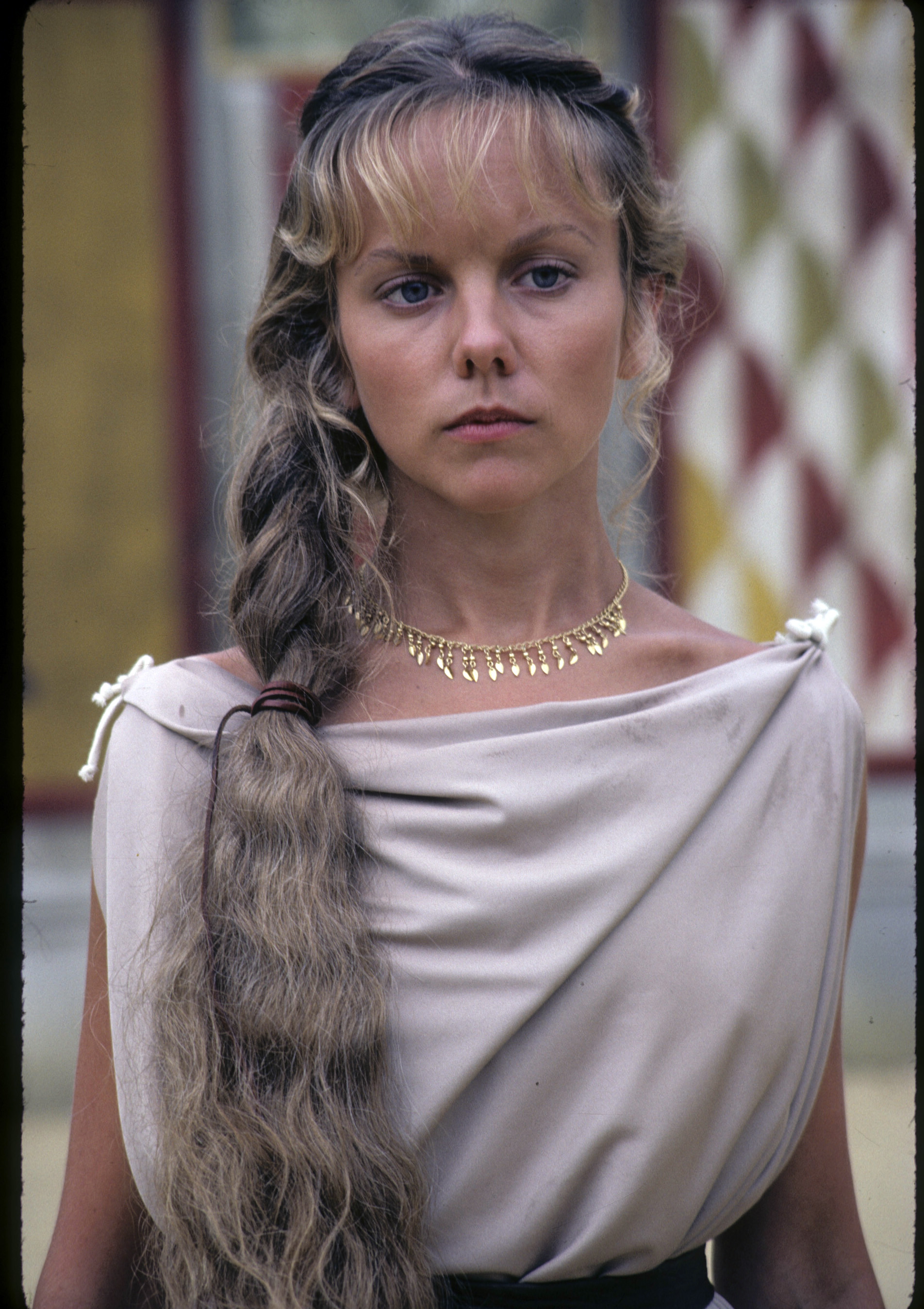 Channeling an ethereal Greco-Roman aesthetic, 28-year-old Linda Purl brought an intense, somber gravity to the May 1984 miniseries "The Last Days of Pompeii". Her youthful face carried a sun-kissed tan and striking bone structure, accented by a gold fringe necklace, a draped ivory chiton, and an elaborate, thick side braid resting softly over her shoulder.