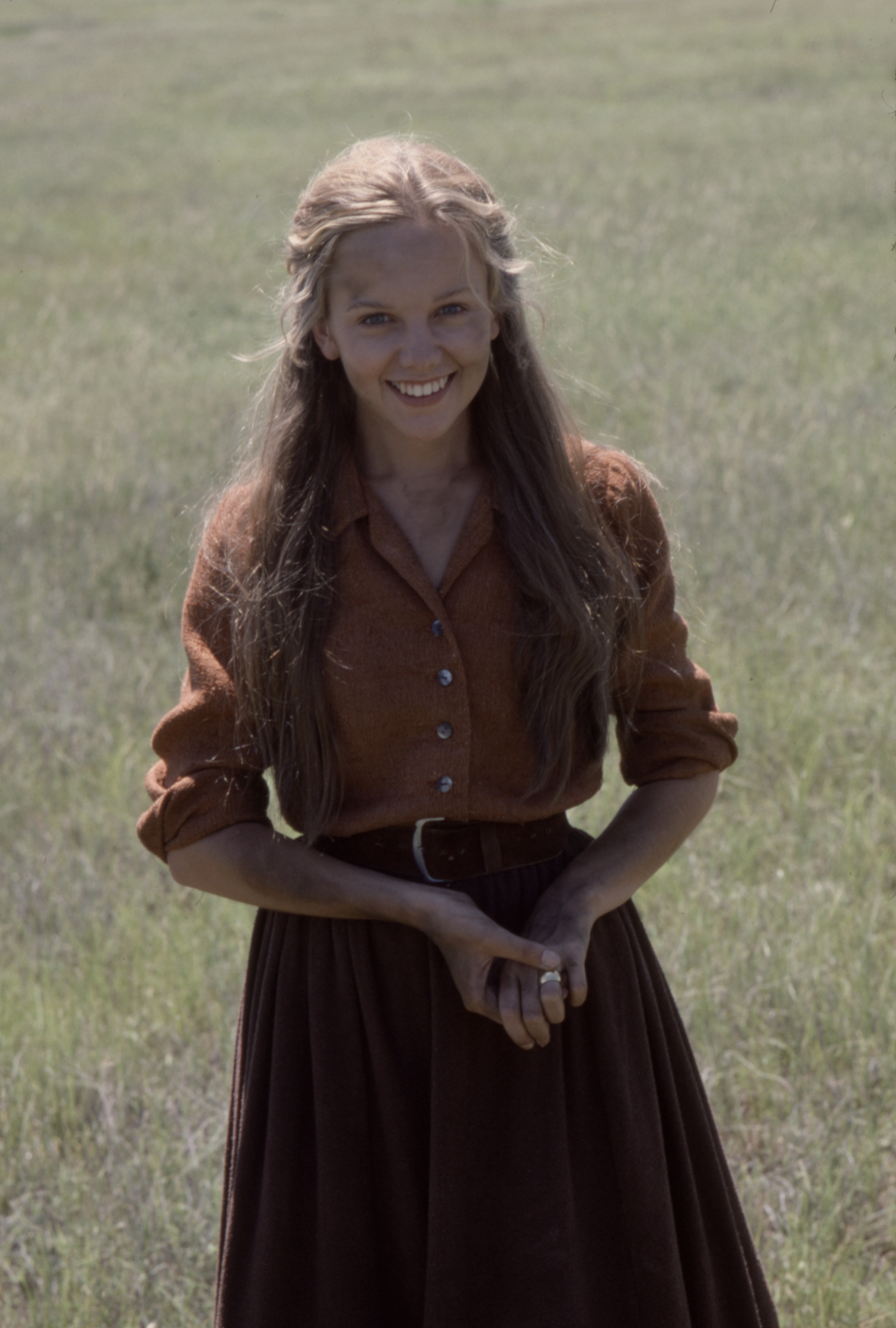 Filming on the Arizona plains in 1978, a youthful 22-year-old Linda Purl beamed with a fresh-faced, sunlit innocence. Dressed as pioneer Molly Beaton in an earthy rust-colored shirt, dark skirt, and loose waves swept off her face, she perfectly embodied the rustic, natural aesthetic of her late 1970s television era.