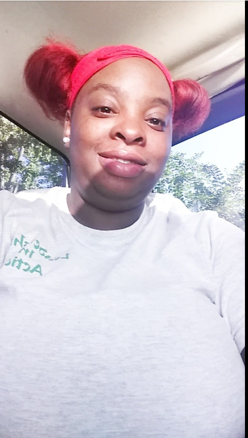 A softly lit selfie of Shaneiqua Elkins, mother of Shamar Elkins’s children, shows her seated in a car, sunlight catching her face and highlighting her red headband and matching hair. | Source: Facebook/Shaneiqua Elkins