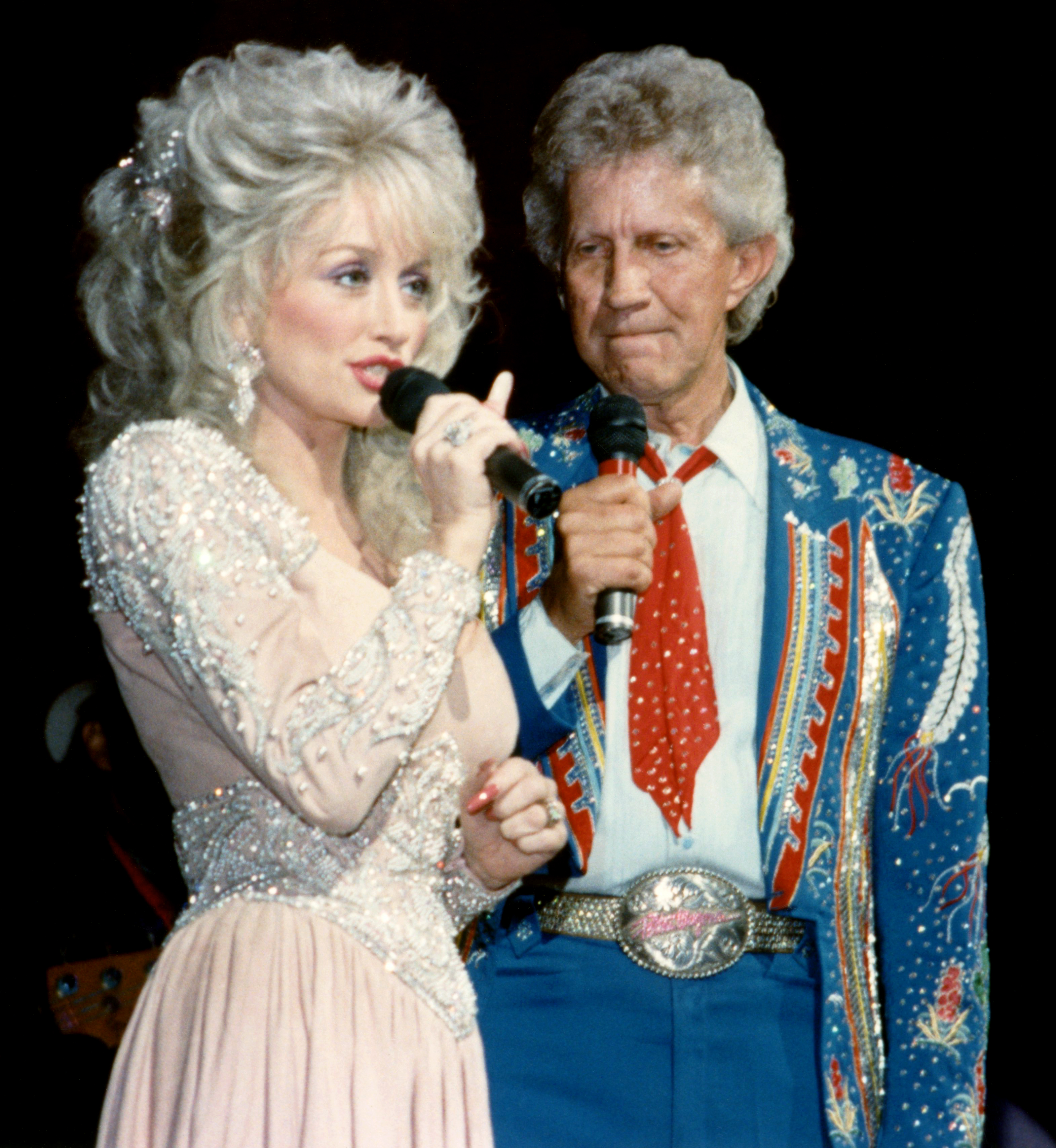 Dolly Parton (1946 - 2026), and Porter Wagoner (1927 - 2007), perform together at the Grand Ole Opry in Nashville, Tennessee, in the 1990s, recalling the professional partnership that helped shape the early years of her remarkable career. | Source: Getty Images