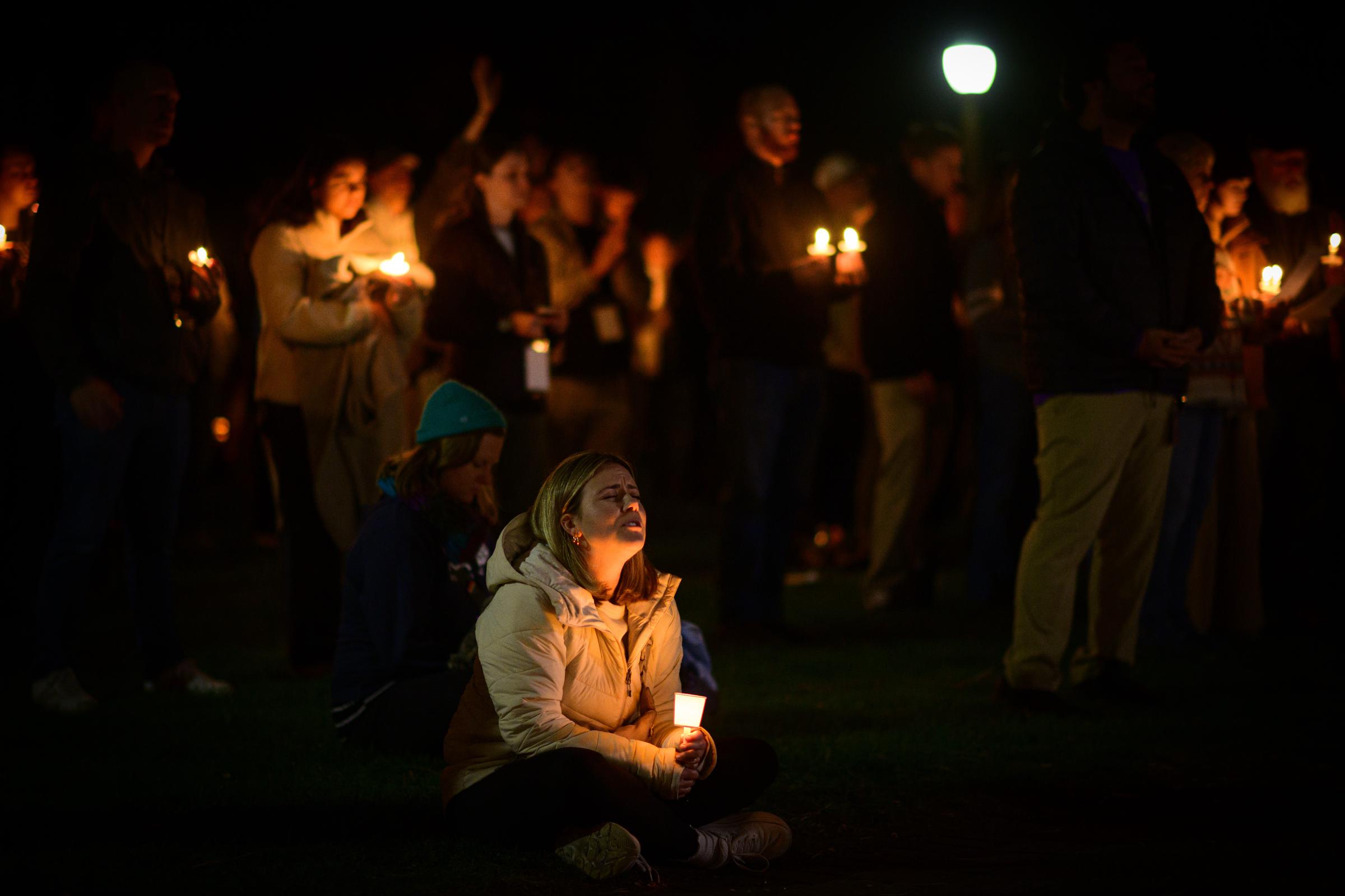 A woman holds a candle while sitting among community members gathered for a vigil after the Silver Rail Elementary School shooting. | Source: Getty Images