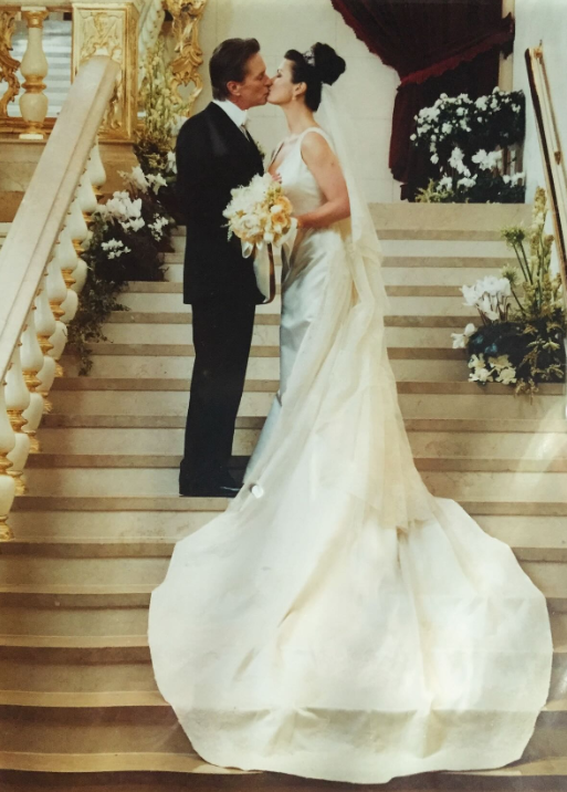 Michael and Catherine pause for a kiss on the grand staircase during their wedding celebration. Looking back on the day 25 years later, Catherine recalled an atmosphere filled with flowers, candlelight, and music from a Welsh choir. | Source: Instagram/catherinezetajones