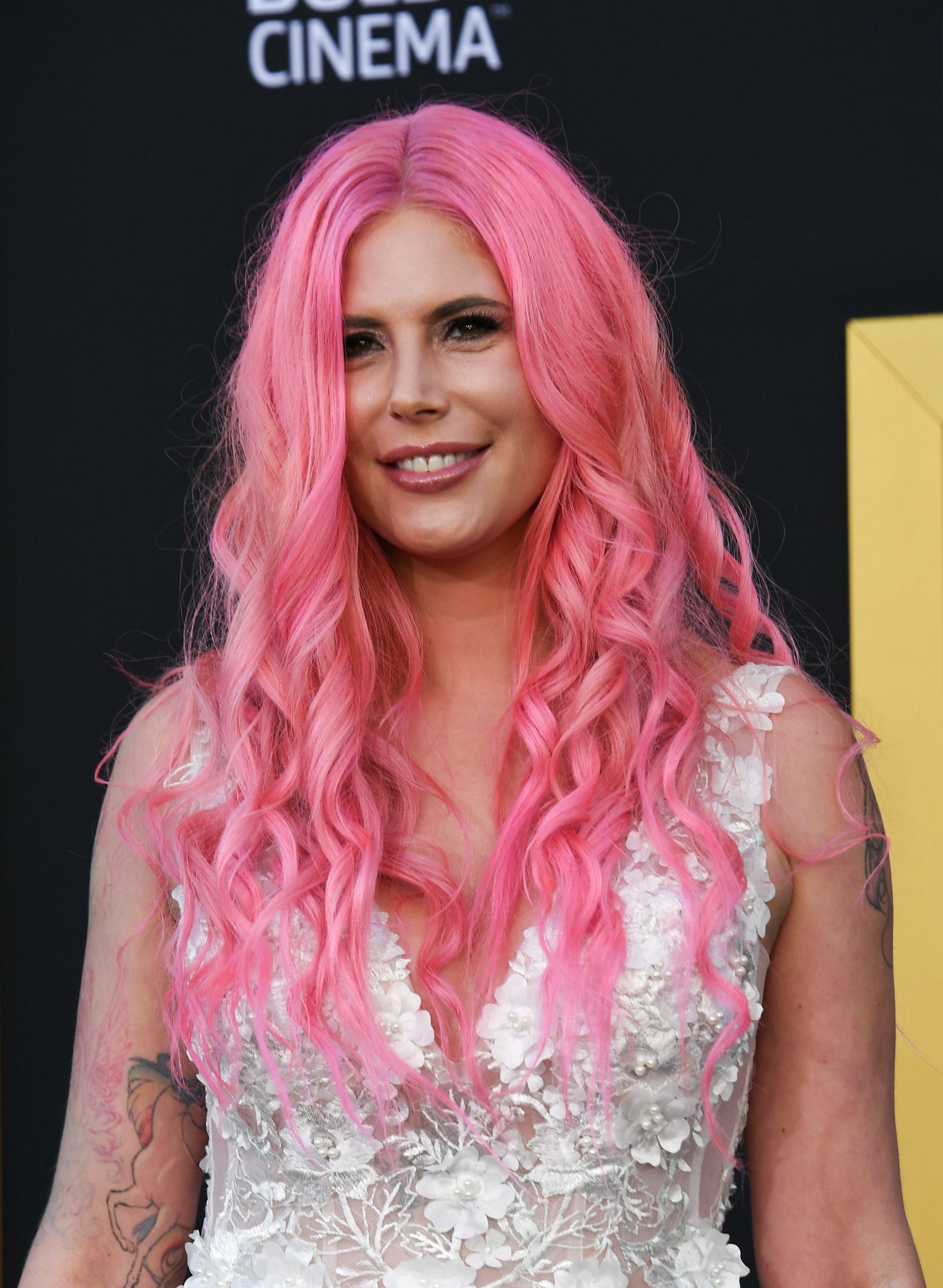 Musician Cleo Rose Elliott turned heads at the premiere of "A Star Is Born" at the Shrine Auditorium on September 24, 2018, in Los Angeles, California. Looking ethereal on the red carpet, she showcased eye-catching, vibrant neon-pink wavy curls parted down the middle, perfectly complementing an intricately embellished white lace gown adorned with delicate floral appliqués. | Source: Getty Images