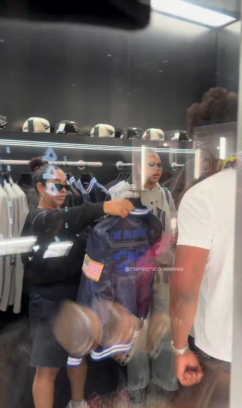 Jay-Z, seen in a white T-shirt at right, stayed close to his daughter as they browsed merchandise together during the Reasonable Doubt anniversary celebrations in New York City. | Source: Instagram/therealnicoleeeeee and fashionbombdaily