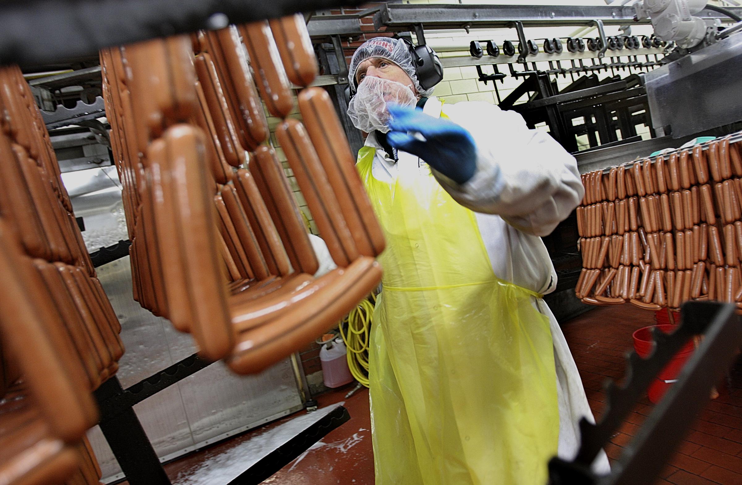 A worker handles links of hot dogs at Kayem Foods on March 24, 2009, as the company prepared its new Fenway Frank ahead of its debut at Fenway Park. | Source: Getty Images