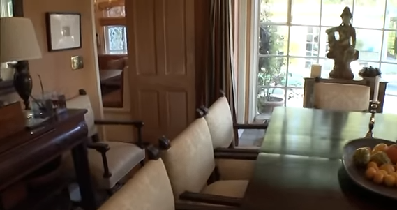 Lisa Rinna's dining room entryway features a rich dark wood sideboard, vintage-style chairs, and warm lighting. | Source: YouTube/@Biography