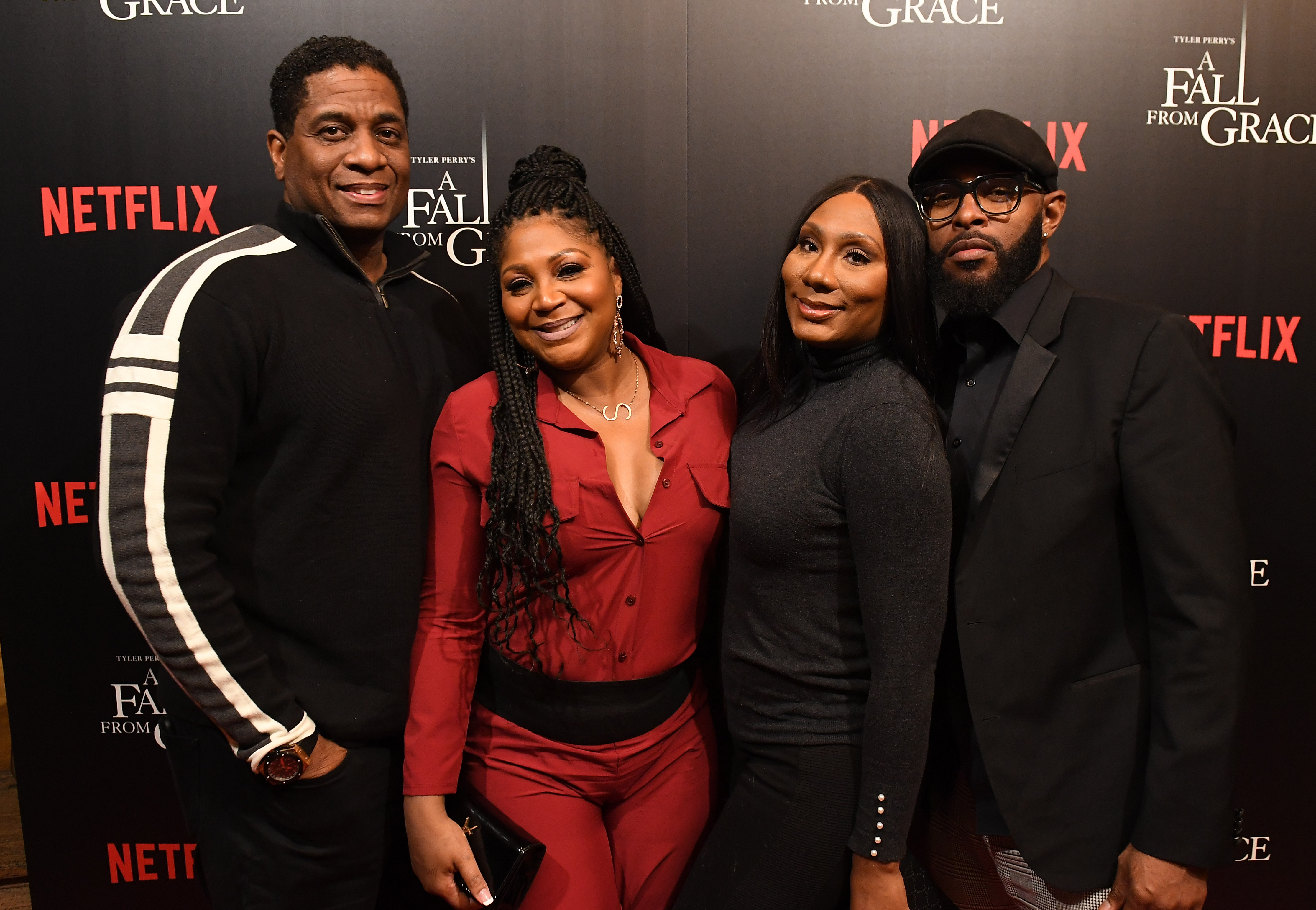 Von Scales, Trina Braxton-Scales, Towanda Braxton, and a guest posed together on the red carpet at Tyler Perry's "A Fall From Grace" VIP screening at SCADshow on January 9, 2020, in Atlanta, Georgia. Scales wore a black zip-front sweater with bold white sleeve stripes, standing beside Braxton-Scales in a rust-red collared ensemble accented with a wide black waist panel, while Towanda Braxton donned a sleek charcoal turtleneck alongside their guest in an all-black suit, cap, and glasses.