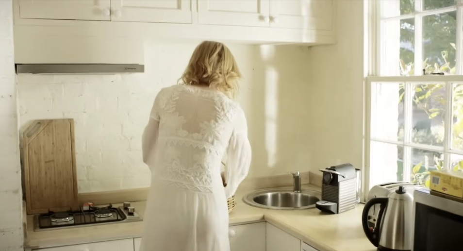 Clean lines and whitewashed brick define the bright corner kitchen, where natural light pours in and everyday essentials sit within reach — blending function with warmth. From a video dated July 20, 2015. | Source: YouTube/Vogue
