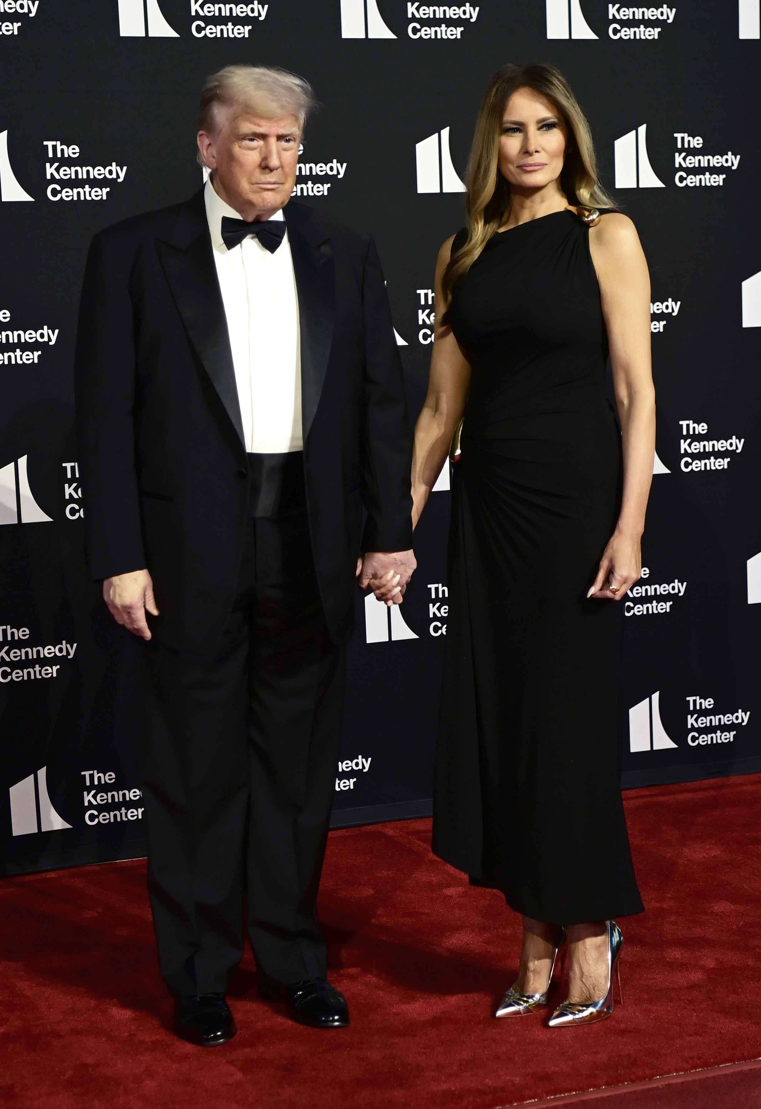 Standing side by side for the cameras, the president and first lady strike a composed pose on the step-and-repeat, framed by the Kennedy Center's signature black backdrop.