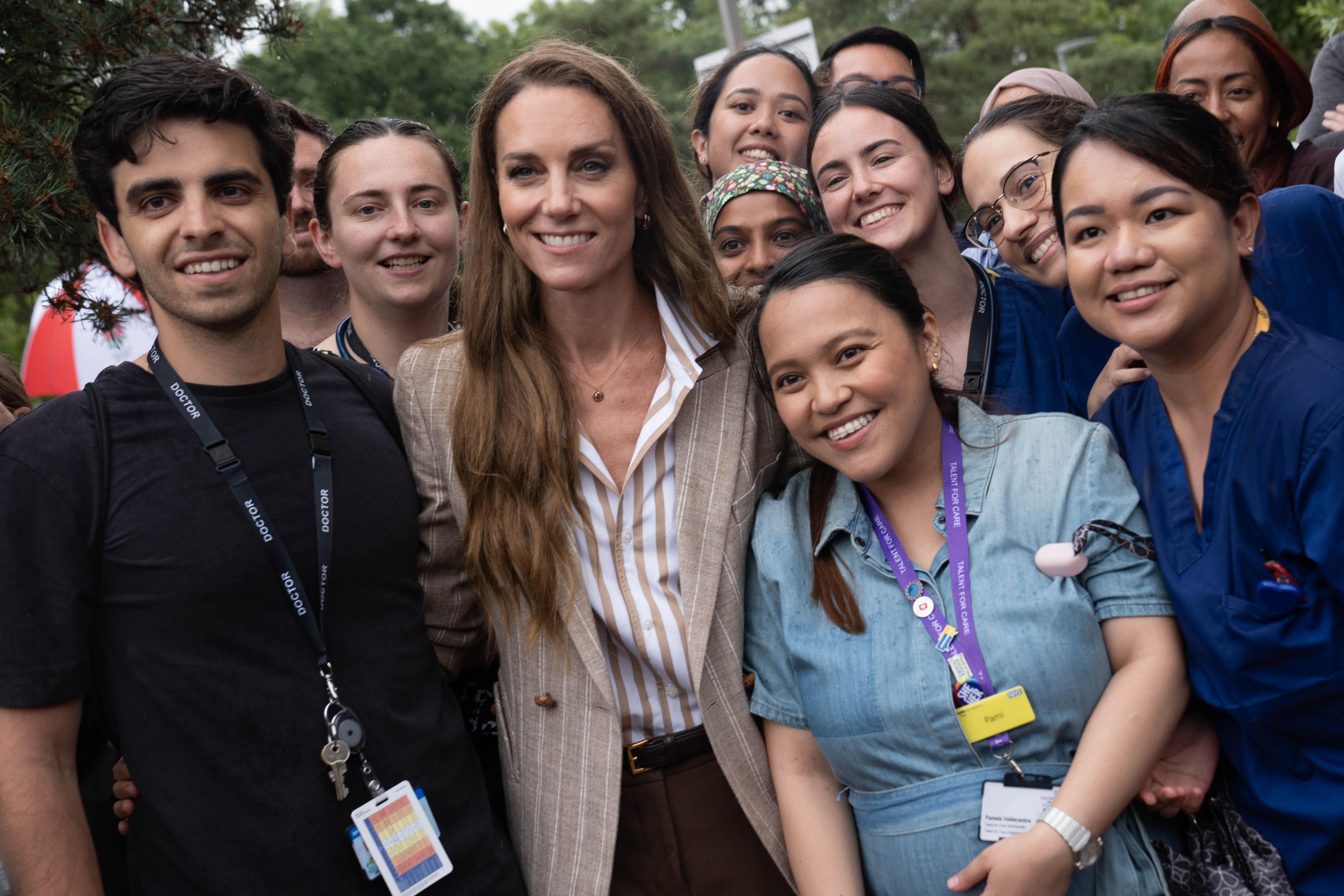 Surrounded by beaming hospital staff, Princess Catherine poses for a group photo, her smile mirroring the joy of those who stood shoulder to shoulder with her.
