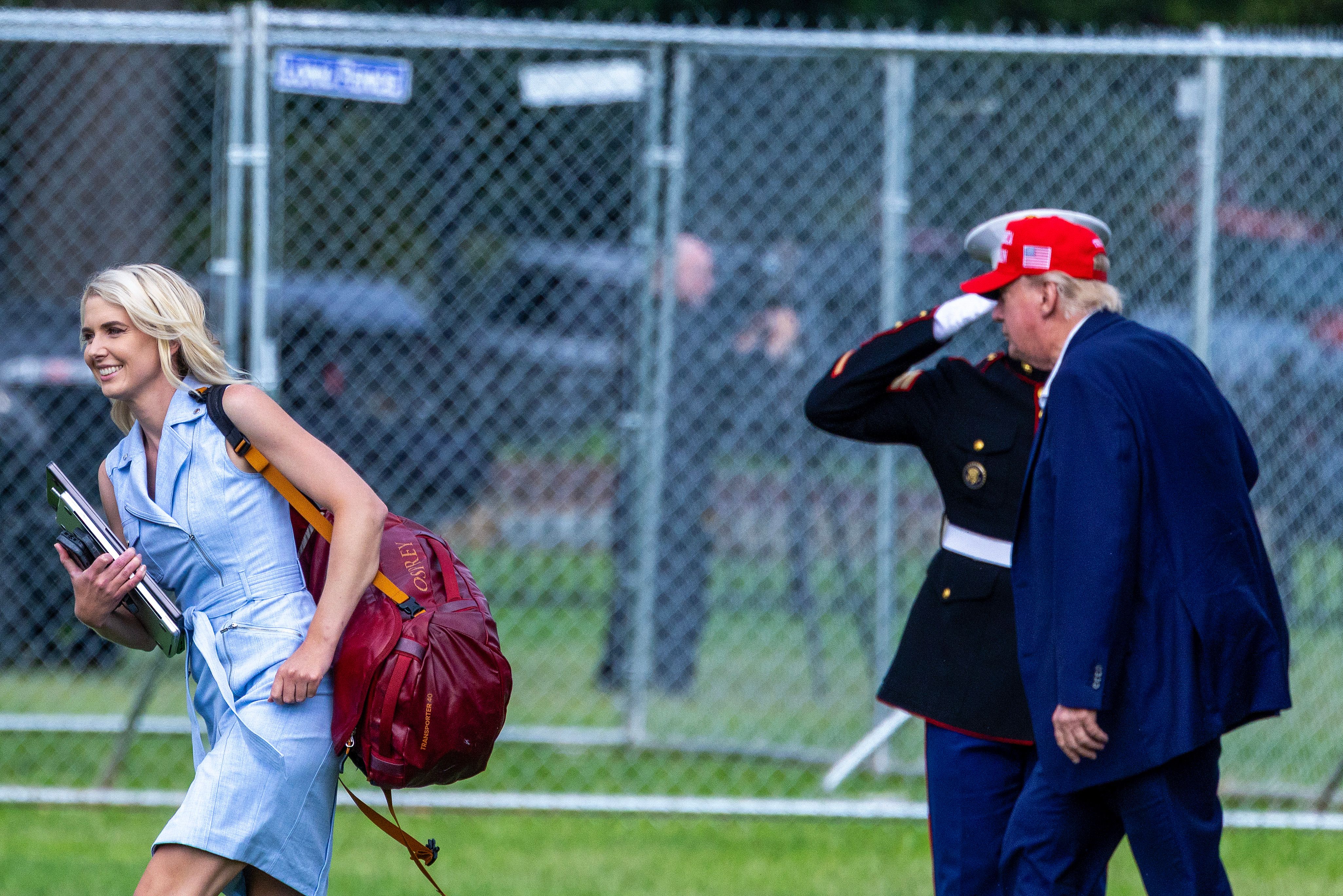 Natalie Harp walks ahead of Donald Trump while carrying the documents that became a defining part of her role in his orbit. Their proximity reportedly drew increasing scrutiny, including from the Secret Service, as concerns about her behavior began to surface. | Source: Getty Images