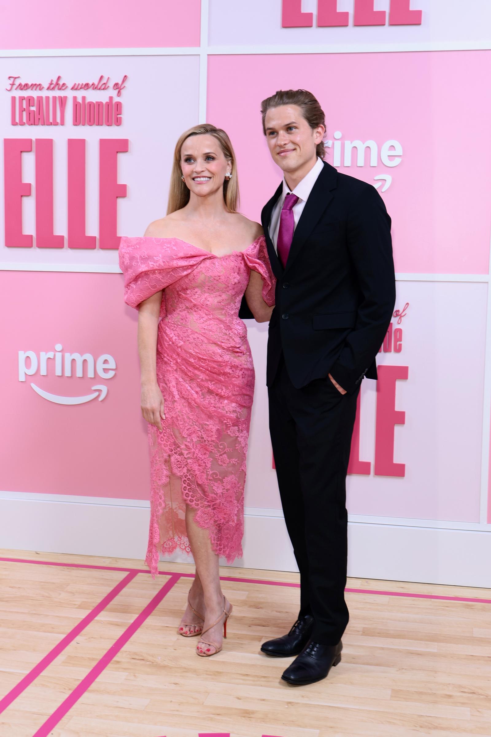 Reese Witherspoon and Deacon Phillippe pose at the 2026 "Elle" Season 1 world premiere in New York City, with her in a pink lace dress and him in a black suit with a magenta tie. | Source: Getty Images