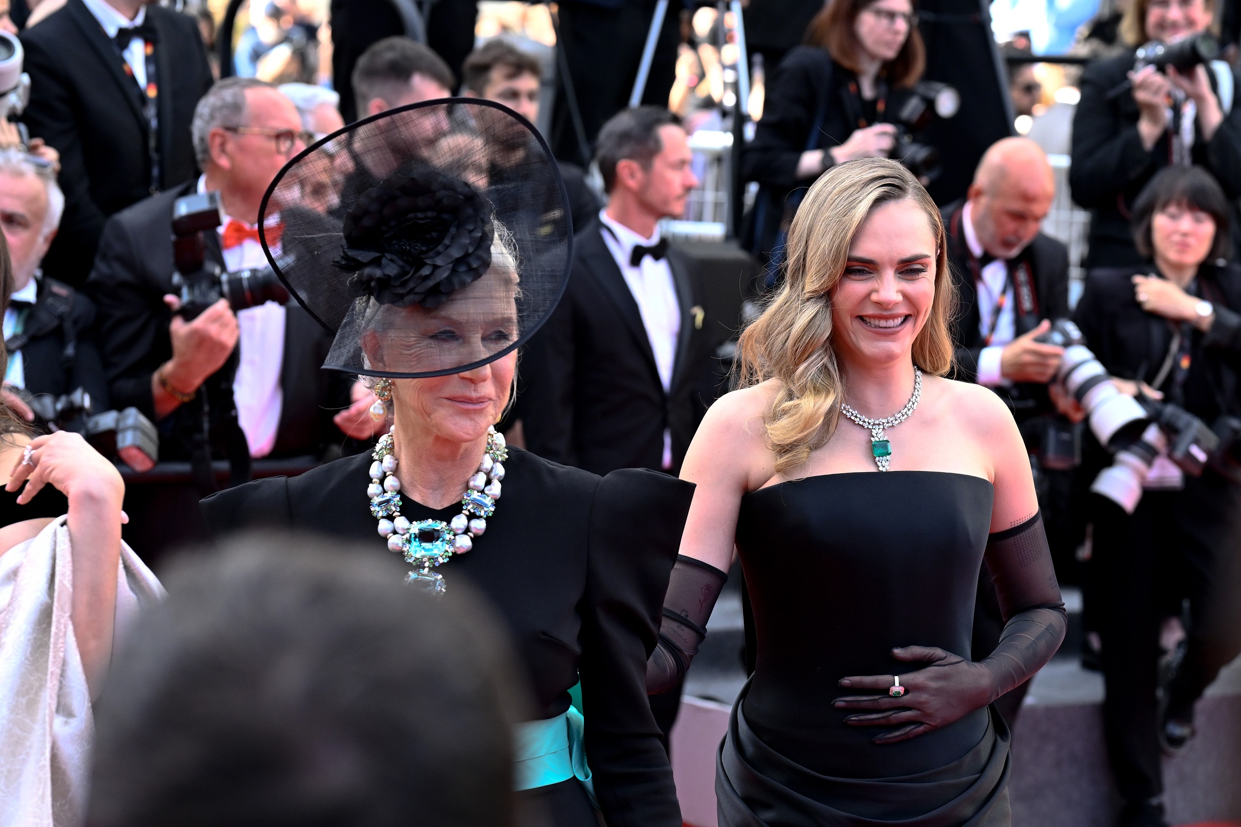 Mirren poses alongside Cara Delevingne, both exuding poise and charm. While Delevingne looks polished in her strapless black gown and sheer gloves, adorned with a vivid emerald and diamond necklace, it’s Mirren’s commanding cascade of seafoam jewels and pearls that steals the spotlight.
