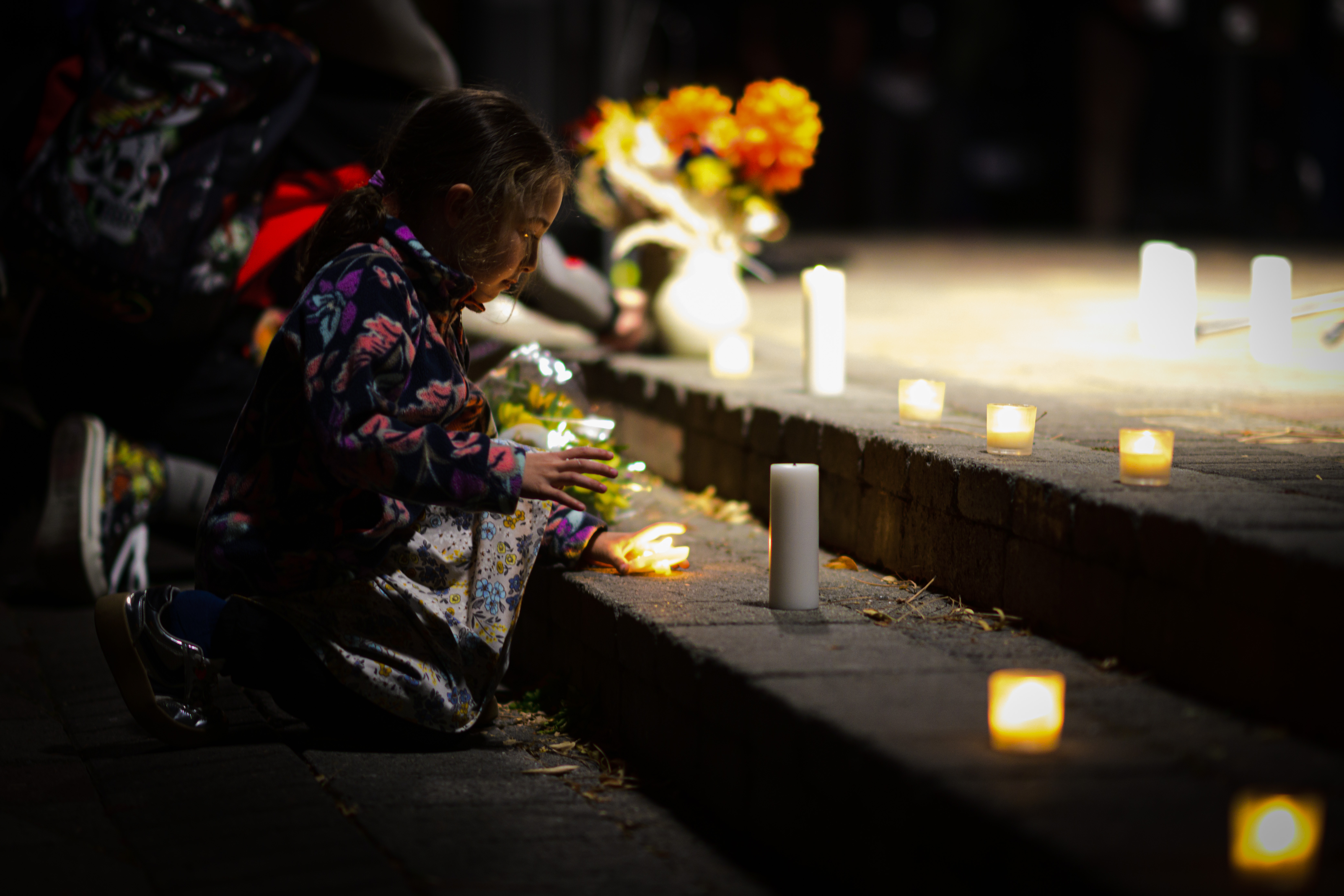 A young girl places a candle beside flowers and other tributes at a memorial honoring those affected by the school shooting. | Source: Getty Images