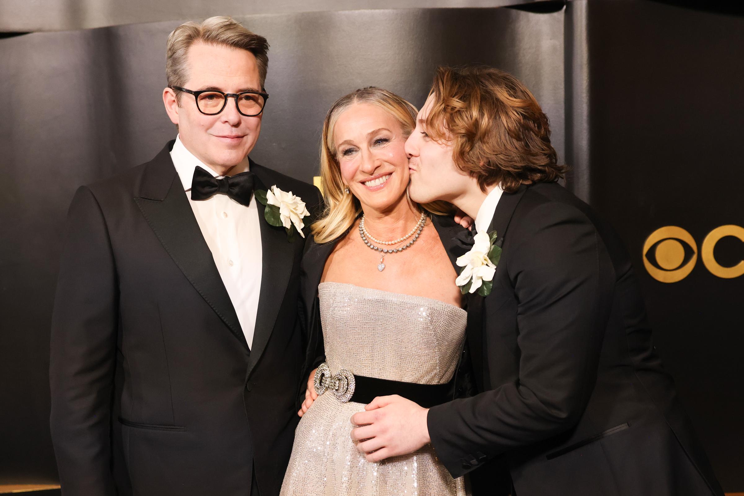 James Wilkie Broderick planting a sweet kiss on Sarah Jessica Parker's cheek, while Matthew Broderick smiles and looks on. | Source: Getty Images