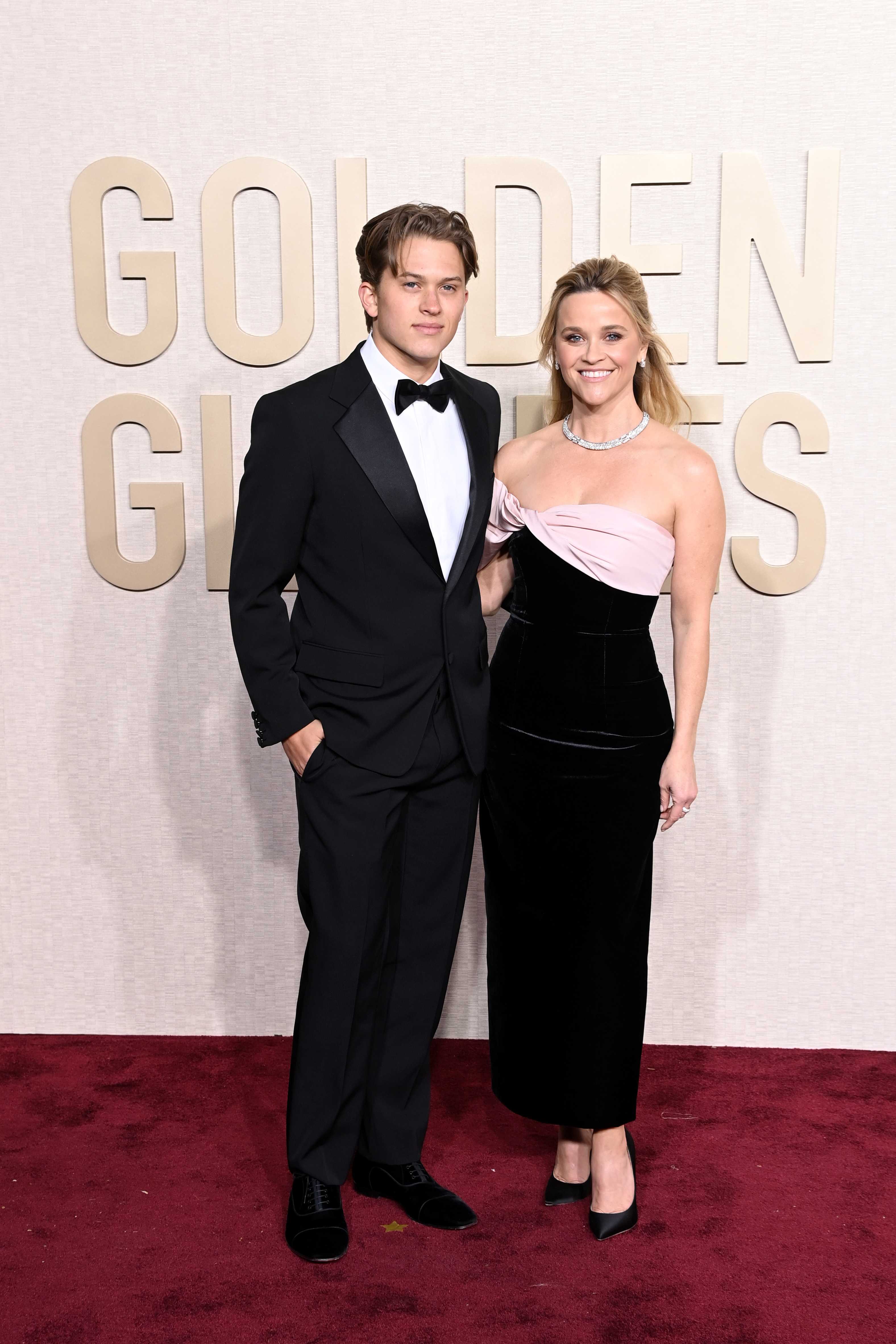 Deacon Phillippe and Reese Witherspoon pose on the red carpet at the 81st Annual Golden Globe Awards, with him in a tuxedo and her in a black-and-pink gown. | Source: Getty Images