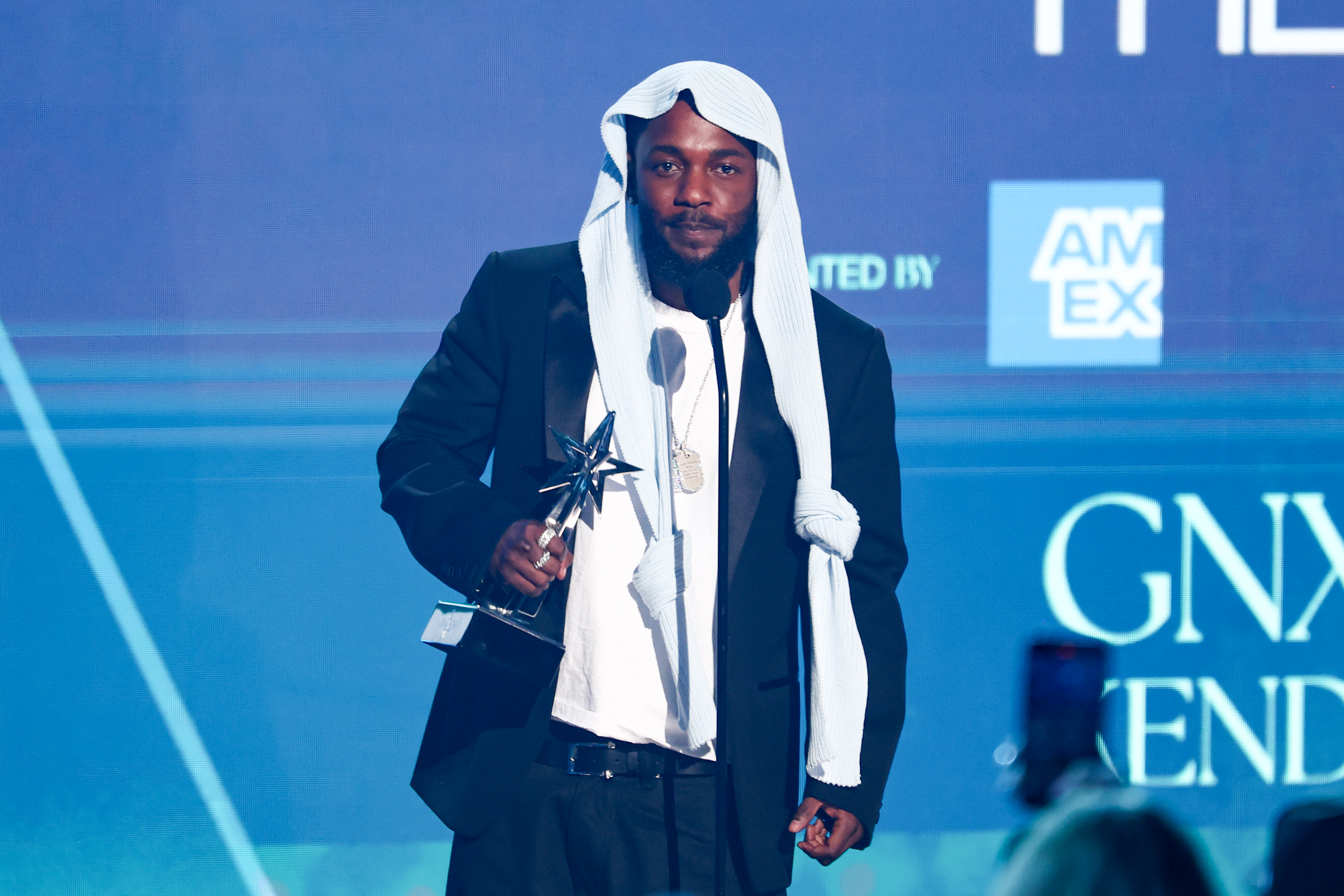 Kendrick Lamar accepts one of his five BET Awards while wearing a black suit and a headpiece that sparked viral buzz online. The moment took place onstage at the Peacock Theater during the 2025 BET Awards in Los Angeles, California.