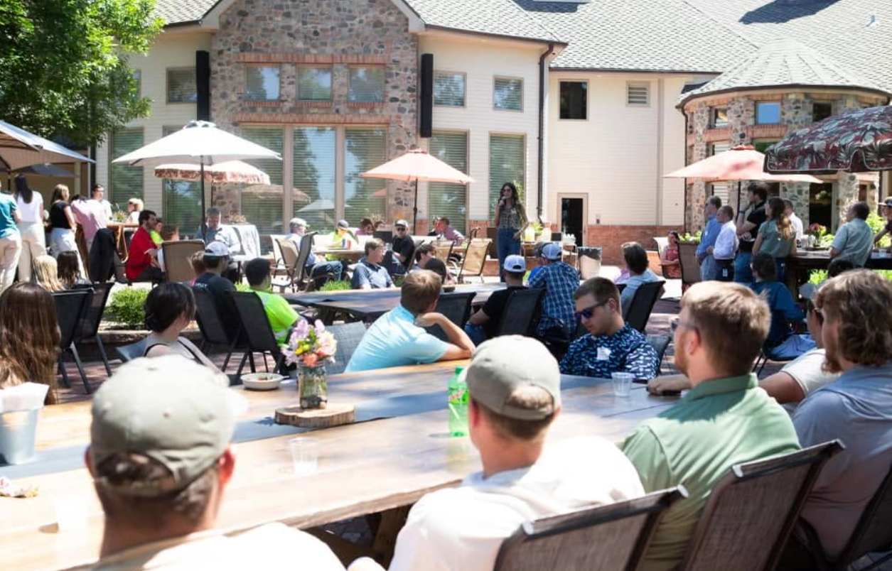 A gathering outside the residence gives a wider sense of the building's scale. Stonework, tall windows, and an upper deck overlook the outdoor gathering area. | Source: Facebook/kristi.noem