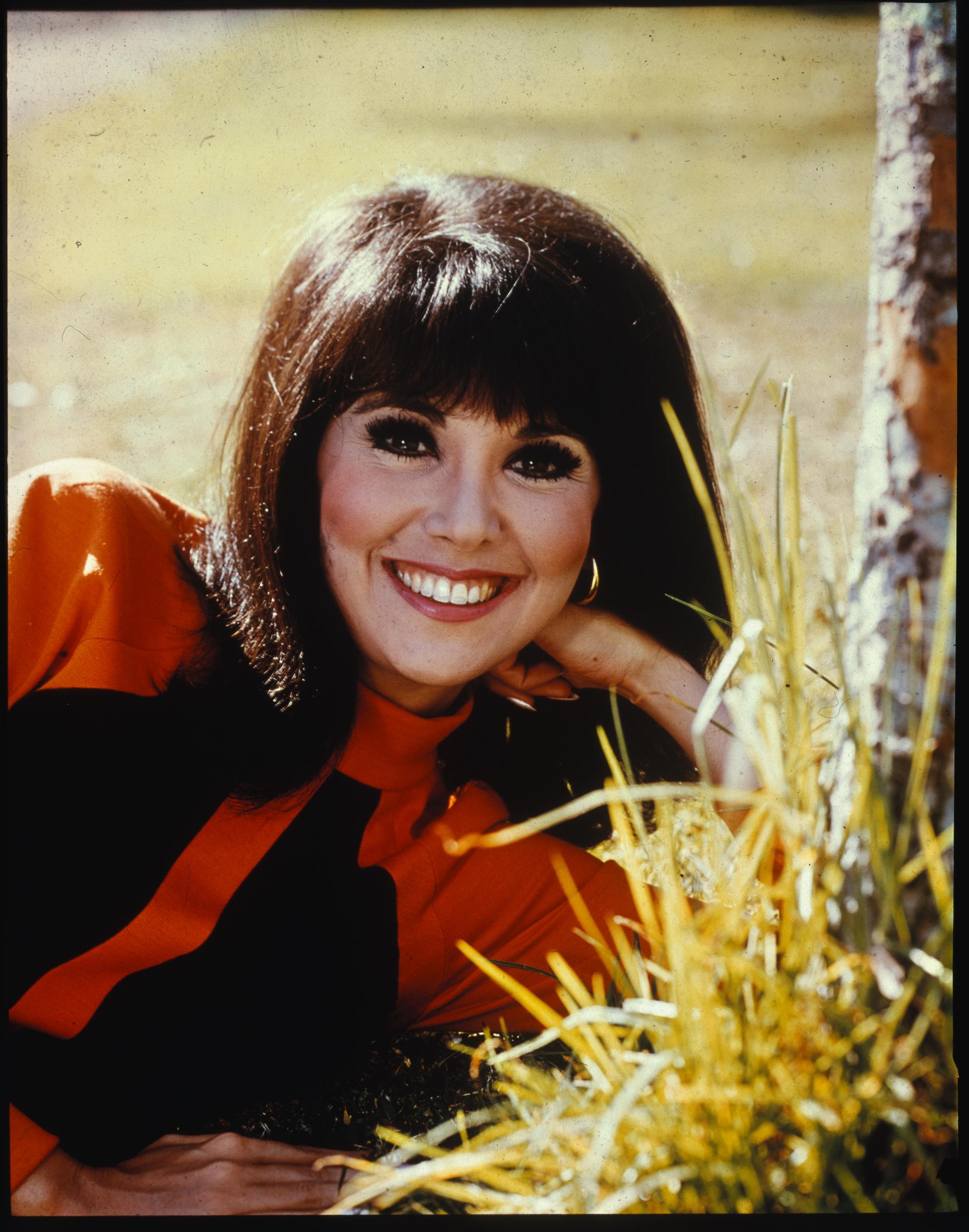 Marlo Thomas smiles brightly while posing outdoors in a striking red-and-black ensemble, capturing the charm and star power that made her a television favorite during her run on "That Girl." | Source: Getty Images