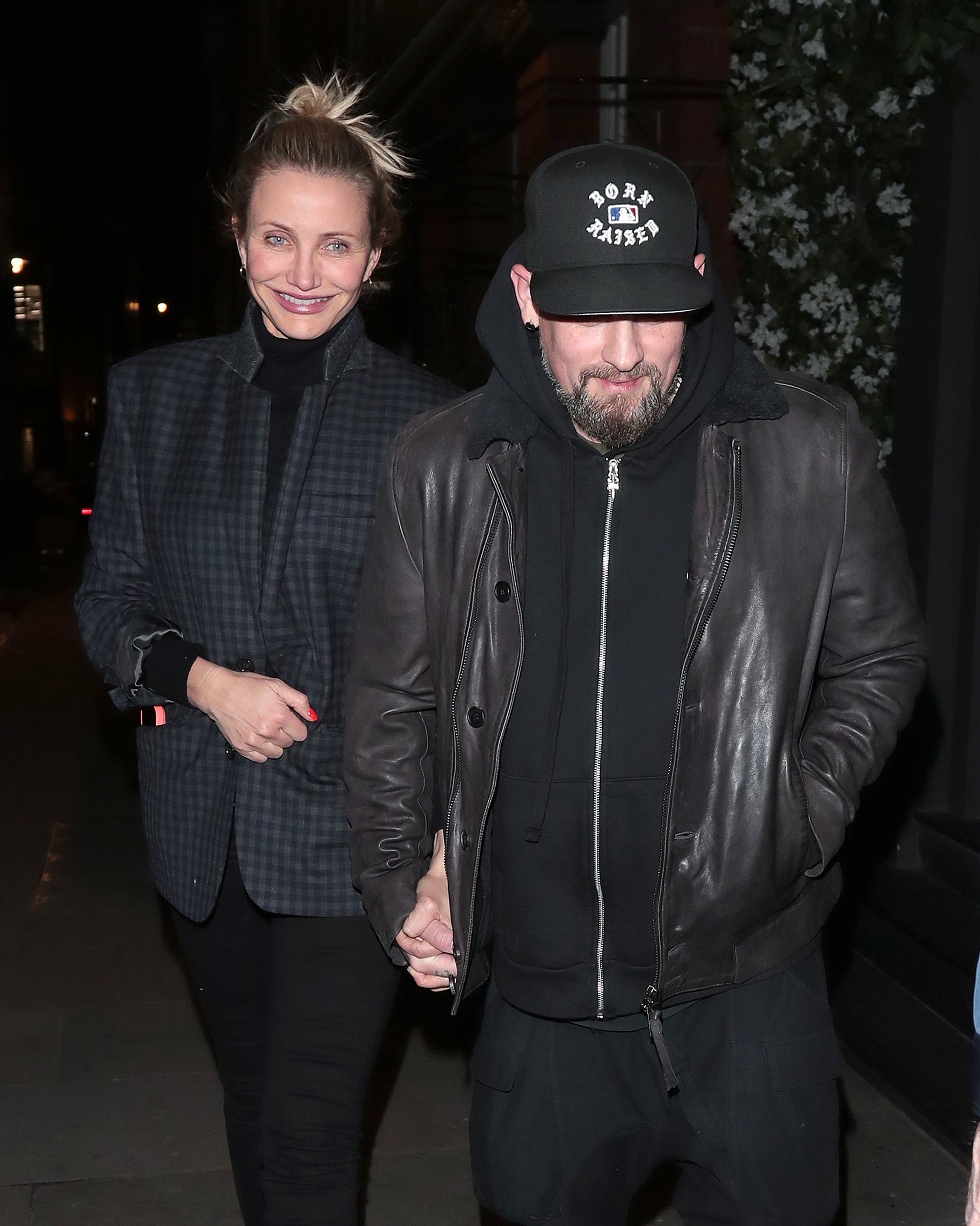 Cameron Diaz and Benji Madden are seen on a night out at Sparrow Italia in Mayfair, London, walking hand in hand as Diaz smiles in a dark plaid coat and Madden keeps it casual in a leather jacket and cap.