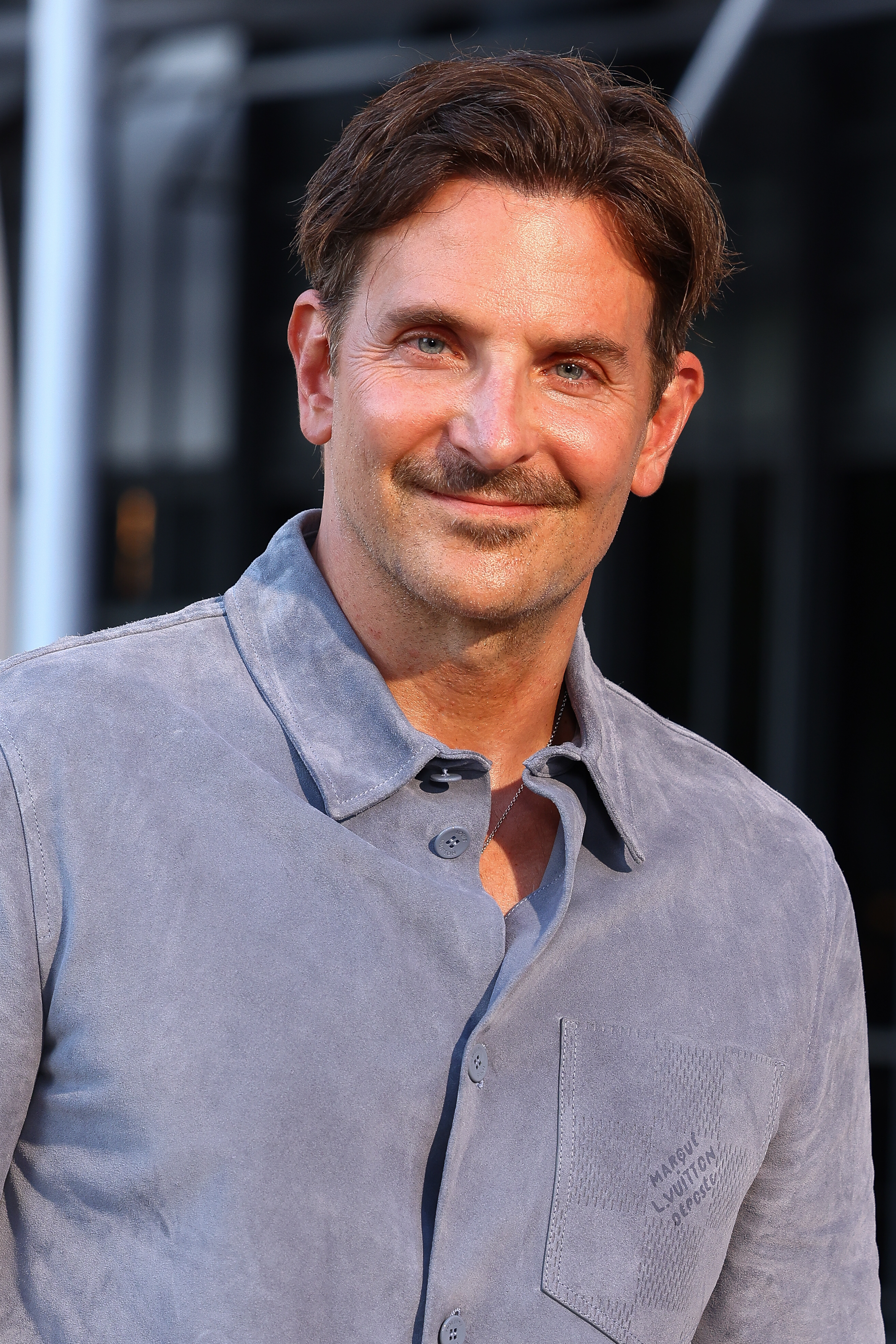 Cooper maintained a relaxed demeanor with a thin, dark mustache above his subtle smile and only a minimal trace of stubble elsewhere on his chin. Although his crow's feet are prominent, his skin looks bright and healthy, as he attended the Louis Vuitton Menswear Spring/Summer 2026 show as part of Paris Fashion Week on June 24, 2025, in Paris, France.