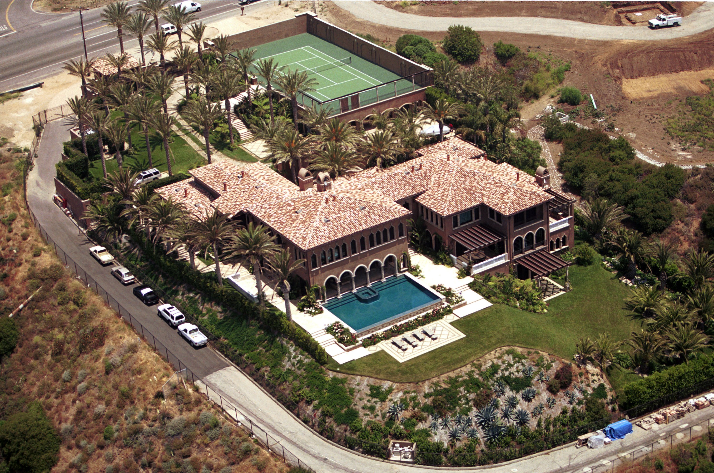 An aerial view captured Cher's oceanside mansion in Malibu, California, on June 18, 2001. The expansive estate features terracotta-tiled roofs, an infinity-edge swimming pool overlooking lush lawns, an elevated private tennis court, and hillside grounds lined with mature palm trees. | Source: Getty Images