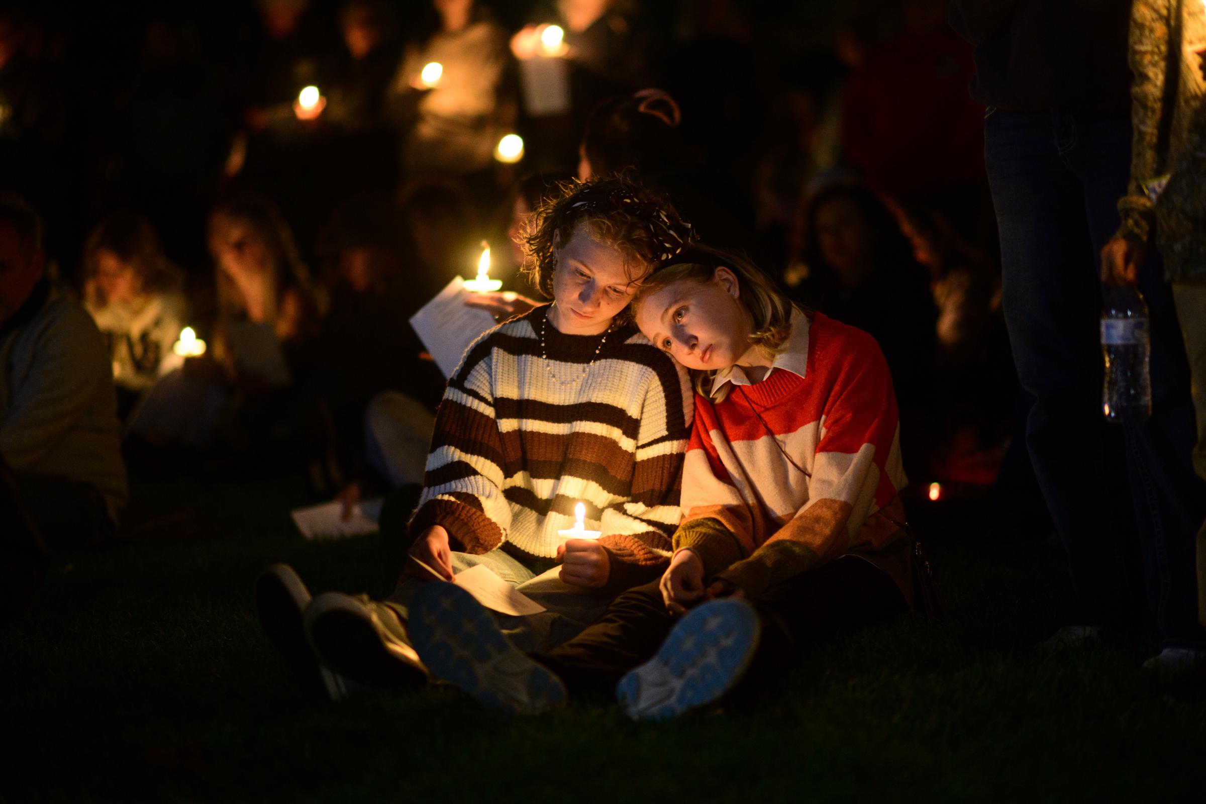 Two young mourners sit close together by candlelight as the Bend community gathers following the tragedy at Silver Rail Elementary School.