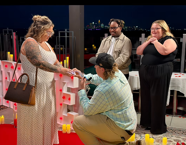 Pumpkin reaches for the engagement ring as Darrin remains on one knee, while Alana Thompson and Dralin Carswell look on with smiles. The rooftop setting glows with candles and red lights as the proposal becomes official. | Source: TikTok/Mama P