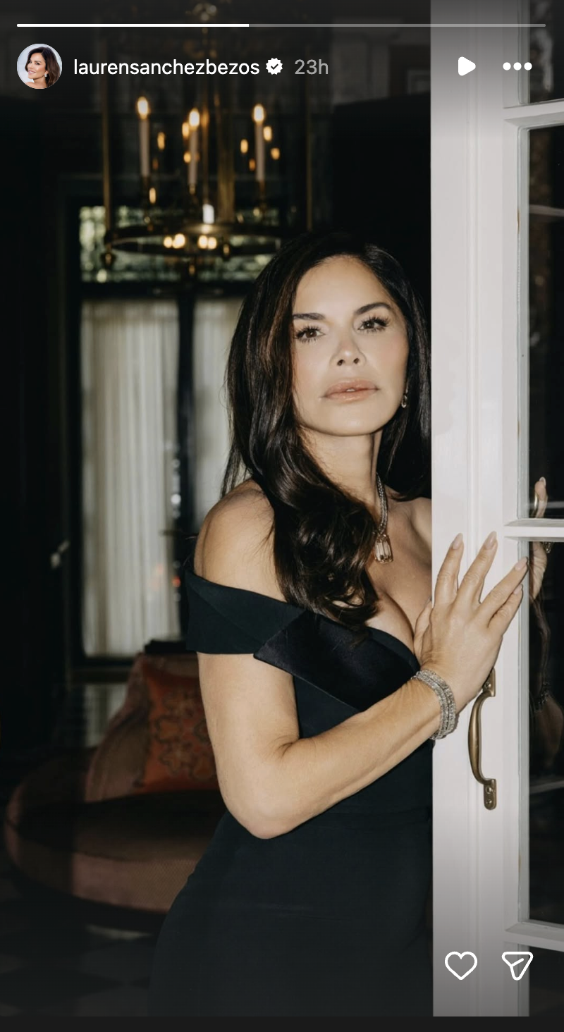 Lauren Sánchez Bezos offered an alluring behind-the-scenes portrait on her Instagram Stories, posing against a glass-paned French door ahead of the White House state dinner on September 24, 2026. Highlighting her sultry, vintage black Alexander McQueen gown, she showcased the piece's sculptural off-the-shoulder neckline, paired with a sparkling diamond pendant necklace, stacked bangles, and softly tousled brunette waves falling over one shoulder. | Source: Instagram/laurensanchezbezos
