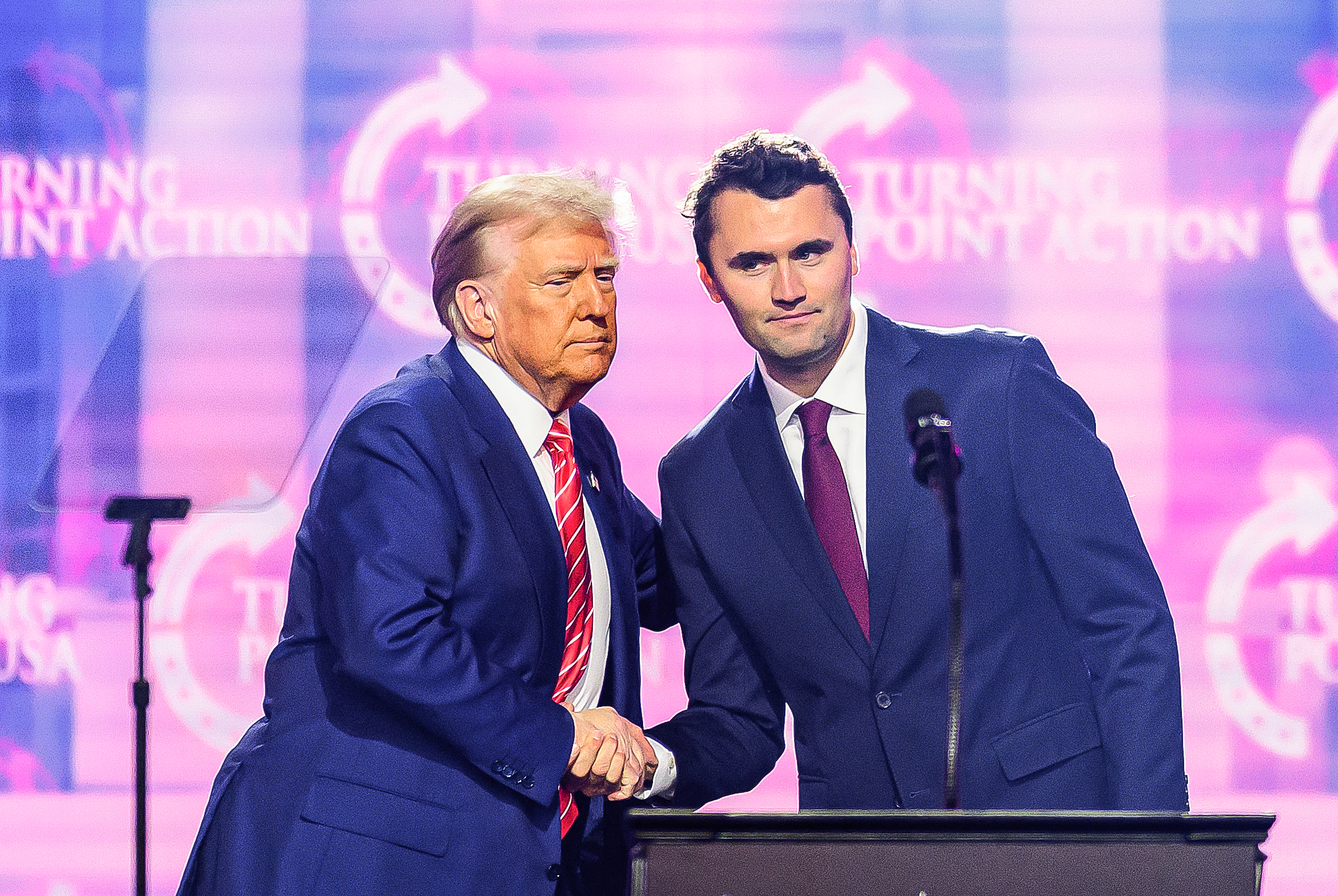 U.S. President Donald Trump and Charlie Kirk shake hands at a major rally for the president in Phoenix, Arizona on December 22, 2024. | Source: Getty Images