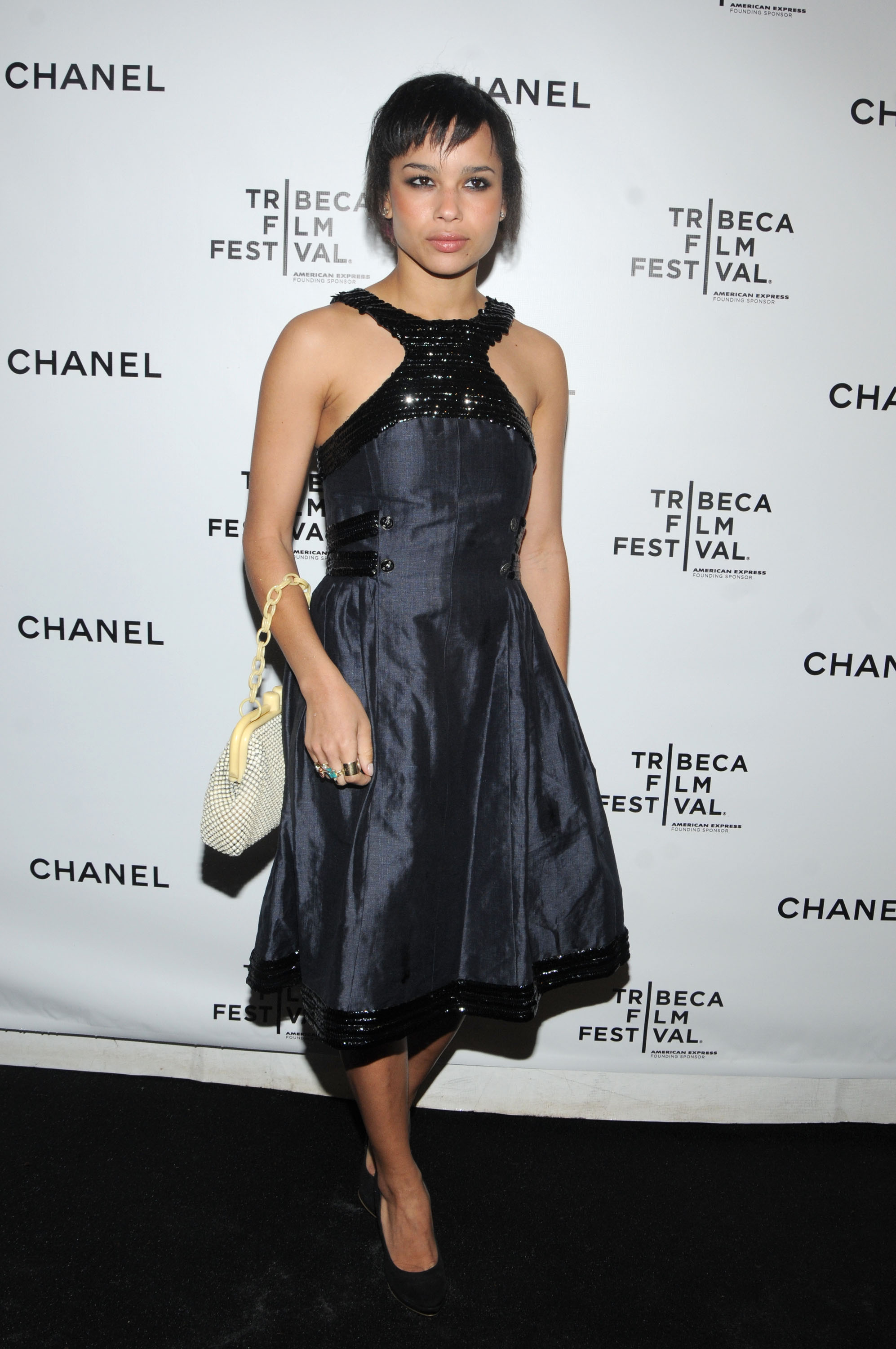Zoë Kravitz attended the 3rd Annual Chanel Dinner Party at AGO at the Greenwich Hotel in New York City on April 28. She wore a halter-style navy dress with black sequin trim and a flared skirt, paired with black pumps and a beaded cream handbag. She finished the look with bold rings and a sleek pixie cut.
