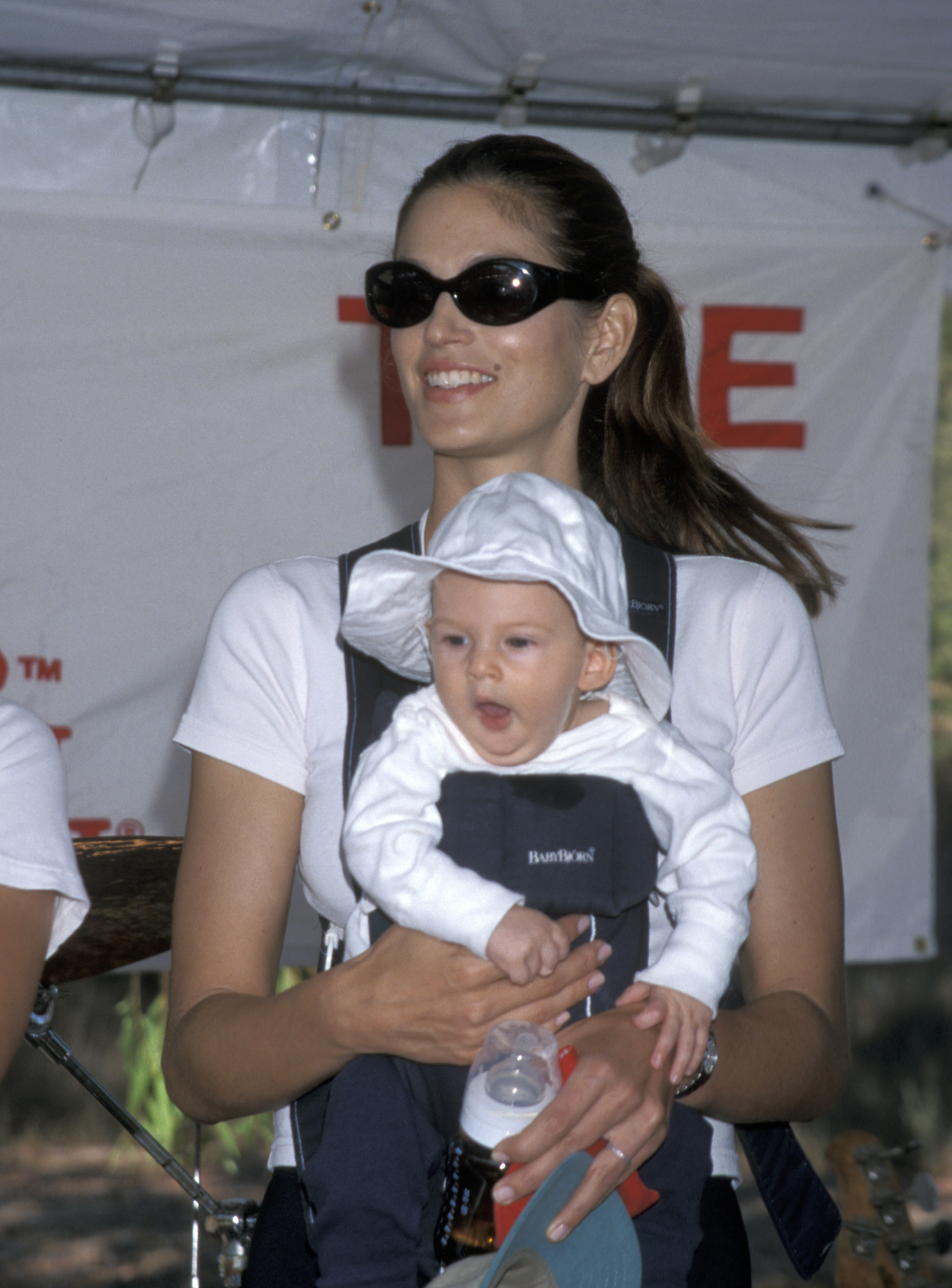 Cindy Crawford carries a baby Presley Gerber at the Take a Hike fundraiser in Malibu in 1999, beaming as she holds him close in a front carrier. Presley, dressed in a floppy white sun hat and matching outfit, yawns softly as he grips his bottle — a quiet reminder of just how tiny and angelic he once was before growing up under the glare of fame. | Source: Getty Images