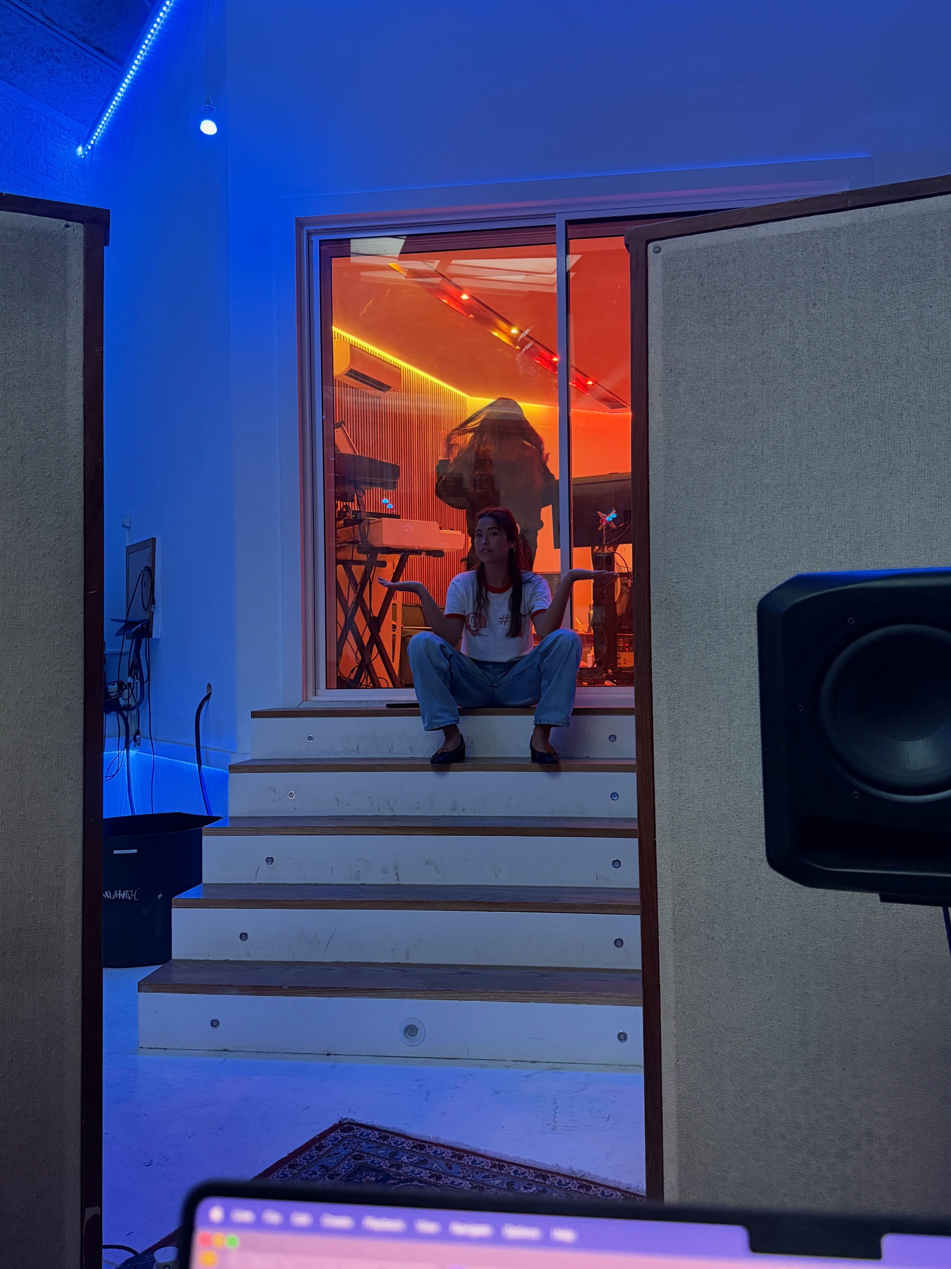 Lola continued the carousel with a glimpse inside the recording studio, sitting on the steps as vivid blue and orange lighting surrounded her. | Source: Instagram/theyoungestyung