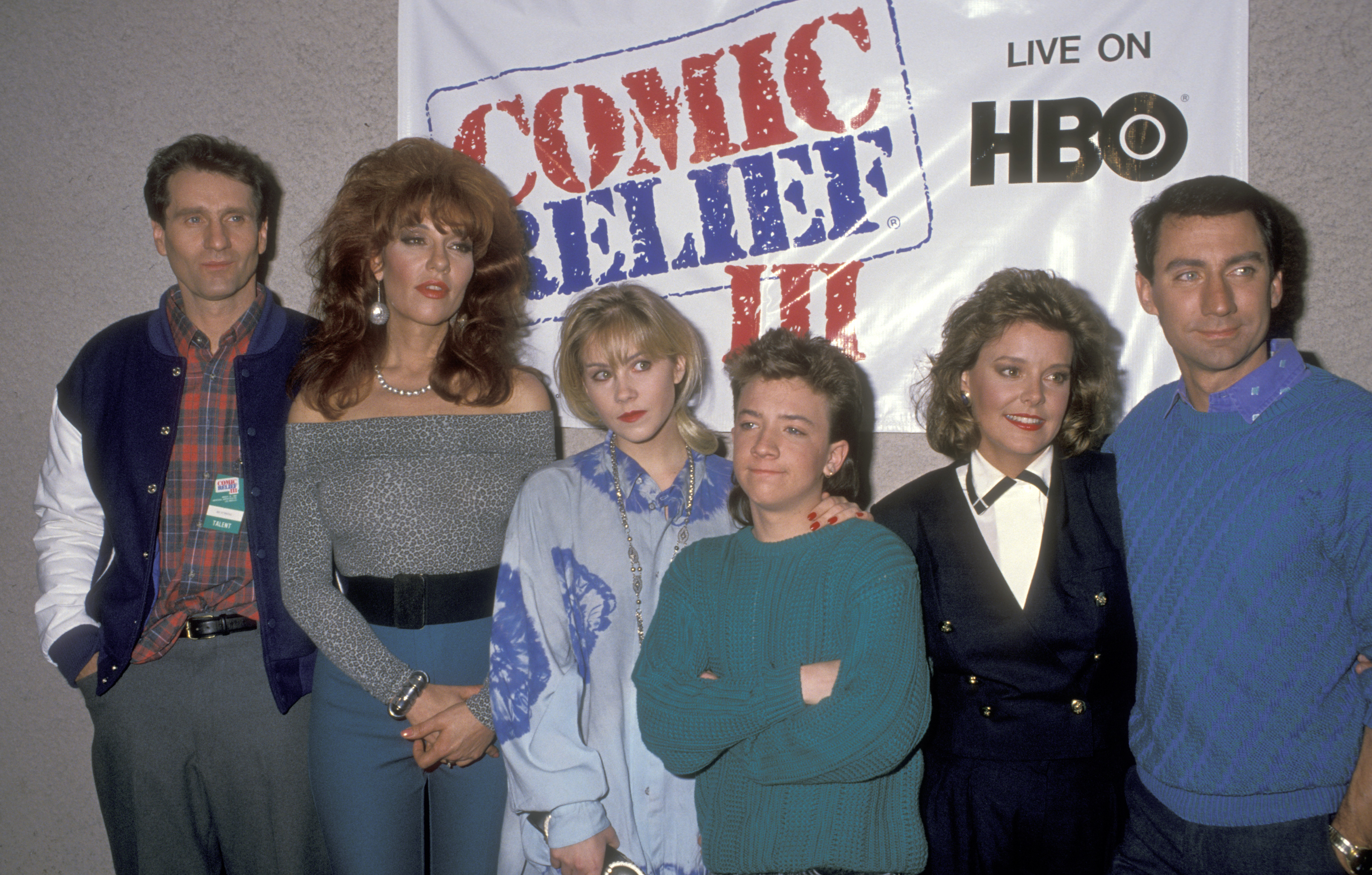 The cast of "Married... with Children"—Ed O'Neill, Katey Sagal, Christina Applegate, David Faustino, Amanda Bearse, and David Garrison—posed together at the Comic Relief III Benefit at Universal Amphitheatre on March 18, 1989, in Universal City, California. The stars showed off classic late-'80s styles, with Sagal rocking voluminous auburn hair, Applegate and Faustino in oversized casual tops, and the group smiling in front of the HBO event banner. | Source: Getty Images