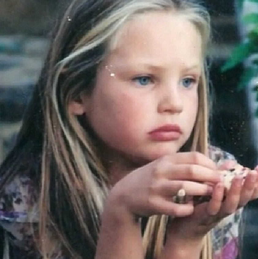 A childhood photo of Candice Swanepoel captures her with long, straight blonde hair as she sits holding a small snack. The throwback offers a glimpse of her early years, long before her South African upbringing led to an international modeling career. | Source: Instagram/candiceswanepoel