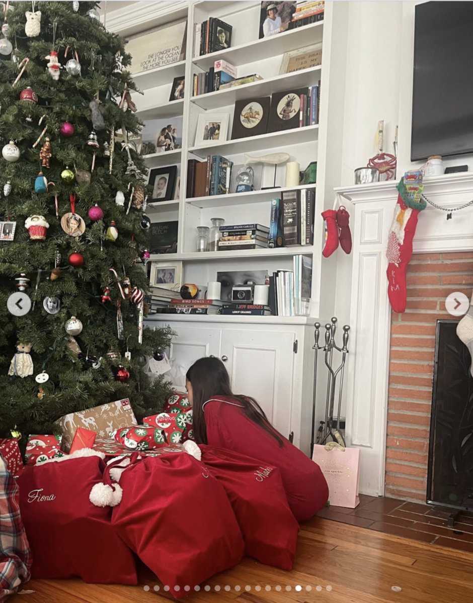 Red Christmas sacks with the girls’ names, including one embroidered “Fiona,” sit beneath the tree beside wrapped gifts and the fireplace. | Source: Instagram/ Mabel Lowe