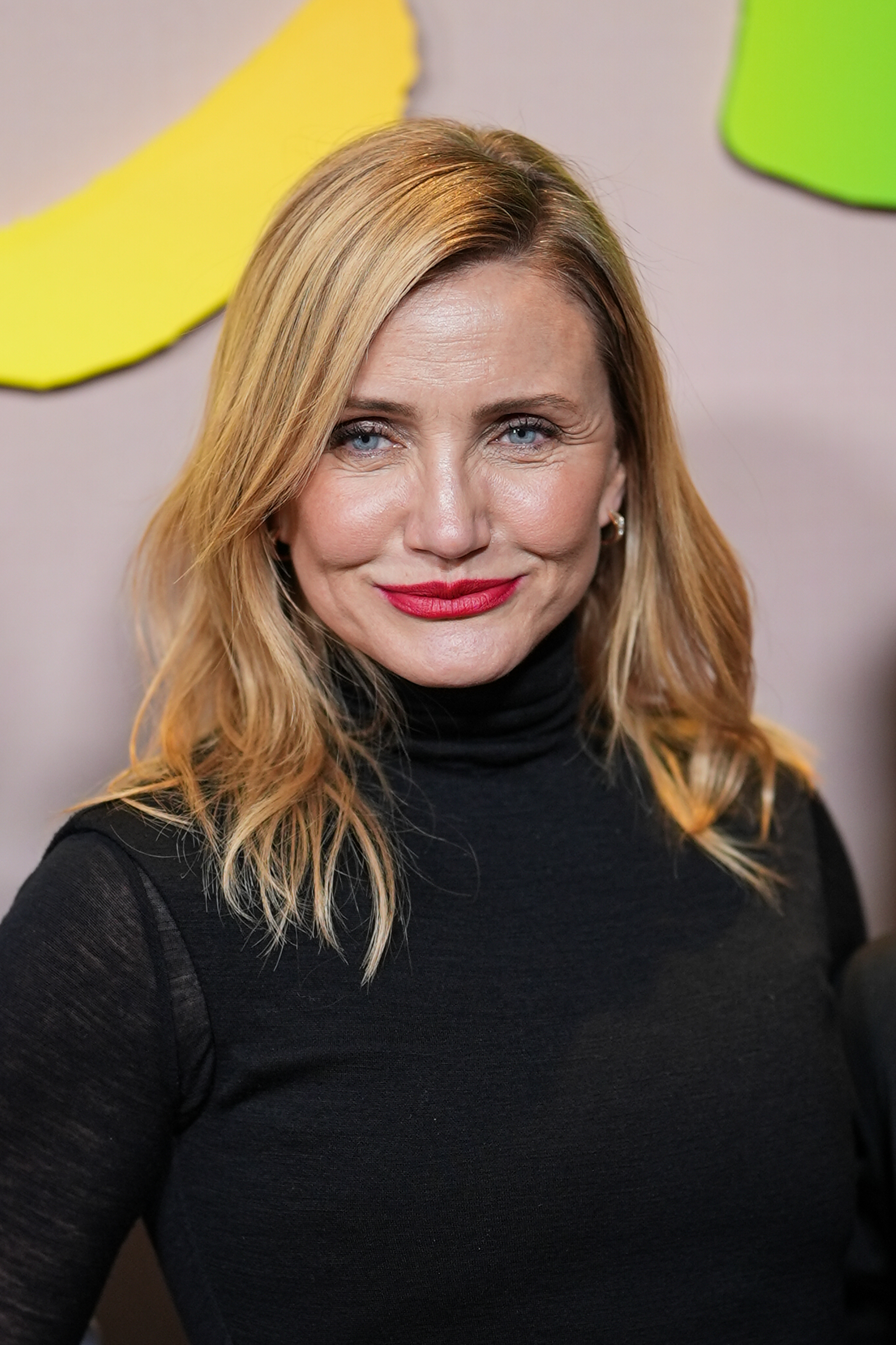 Cameron Diaz turns heads at Apple's "Outcome" world premiere at AMC Lincoln Square Theater, pairing a sleek black turtleneck with bold red lipstick, her softly tousled blonde hair framing a confident, camera-ready smile.