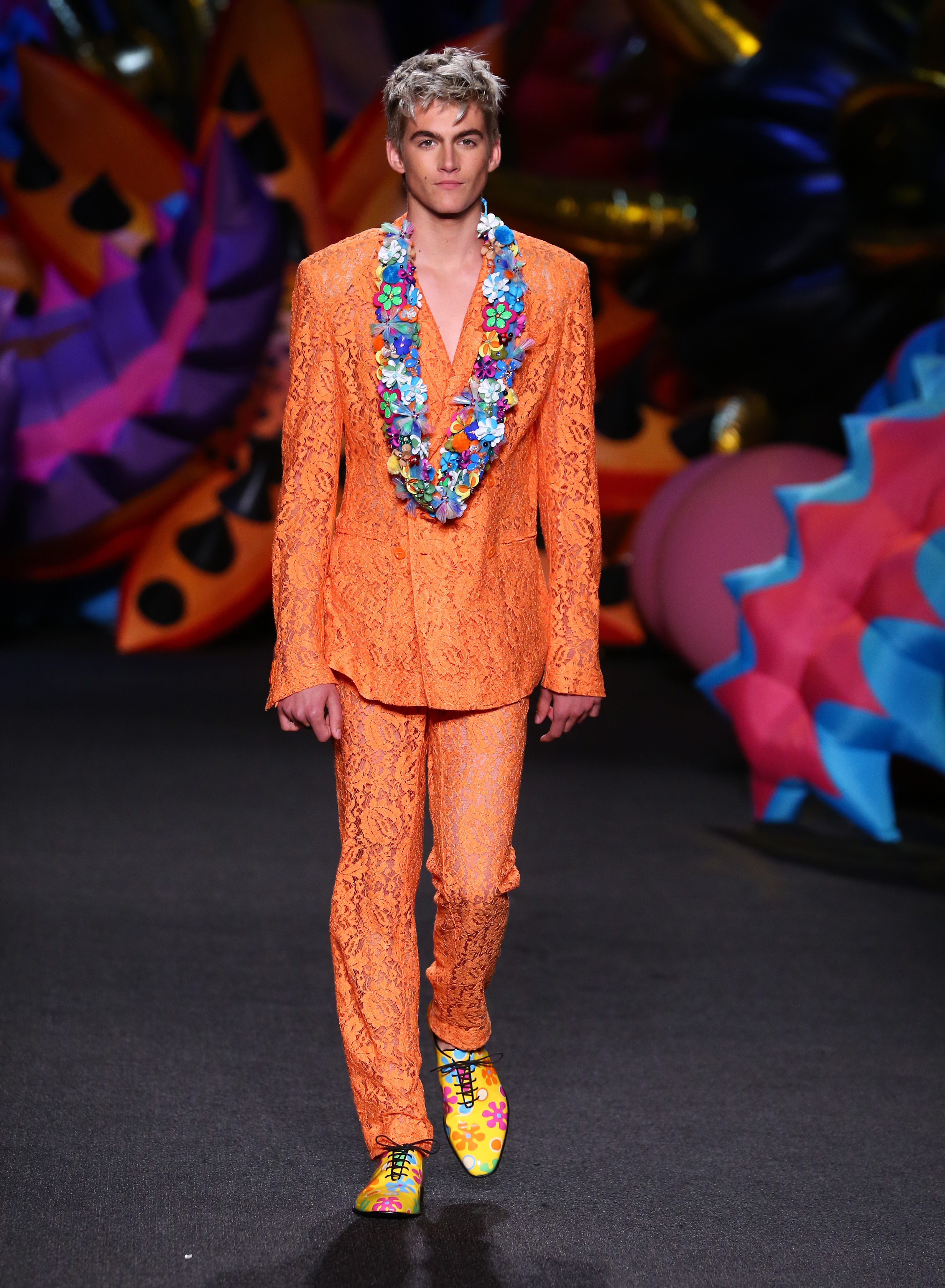 Presley Gerber strutted down the runway during his modeling debut at the Moschino Men's Spring/Summer 2017 and Women's Resort 2017 fashion show in Los Angeles, California, on June 10, 2016, commanding attention in a vibrant lace orange suit accented with a colorful floral lei and patterned dress shoes. | Source: Getty Images