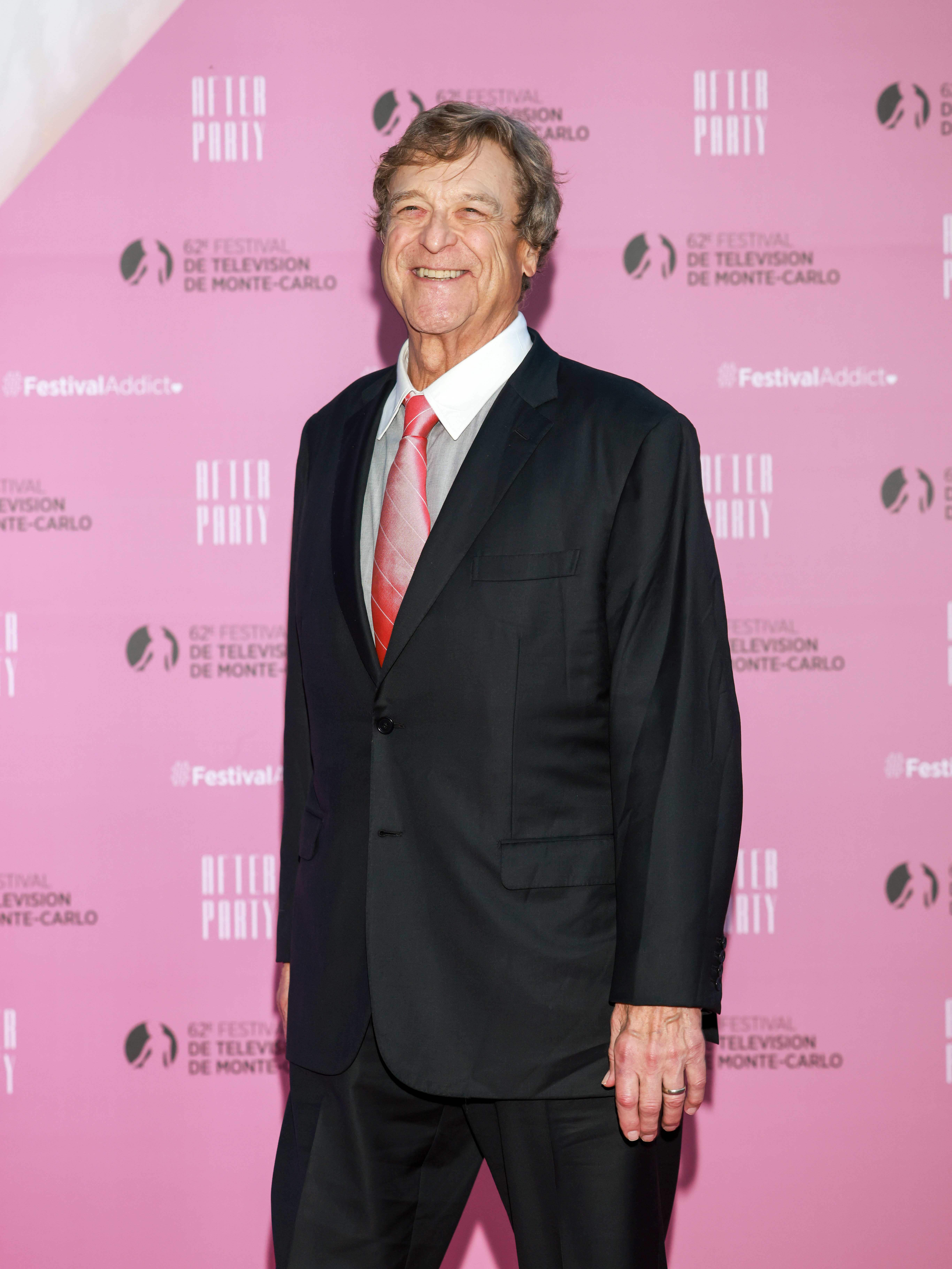 At the 62nd Monte Carlo TV Festival, Goodman showcased his remarkable weight loss in a sharp black suit paired with a silver shirt and red patterned tie, exuding elegance on the pink carpet. His slimmer physique and confident smile highlight a striking transformation and renewed vitality.