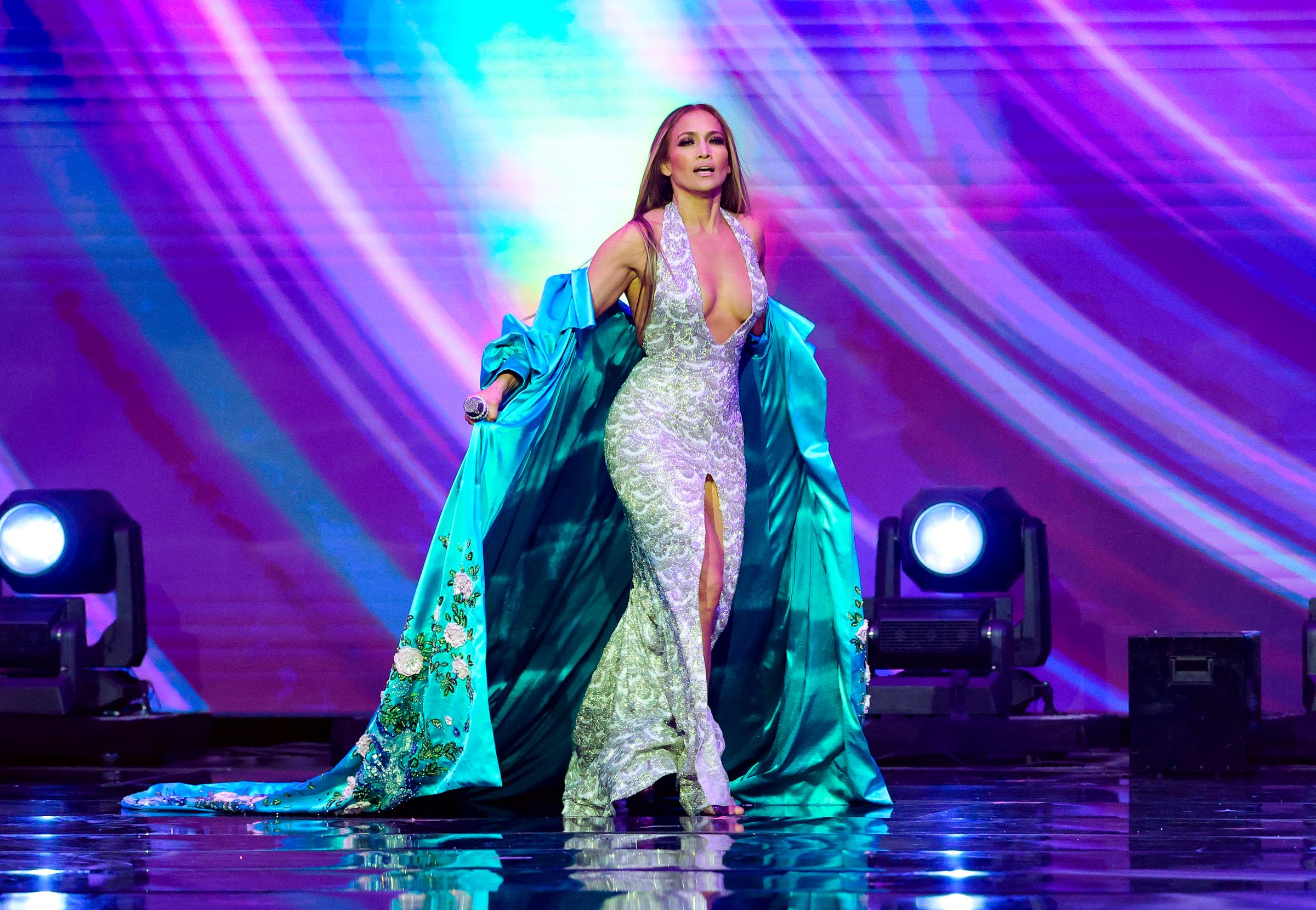 Wearing a silver gown and teal robe, Jennifer Lopez steps onto the AMAs stage on May 26, 2025, in Las Vegas. The multi-hyphenate served as host of the ceremony, making several appearances across musical and presentation segments.
