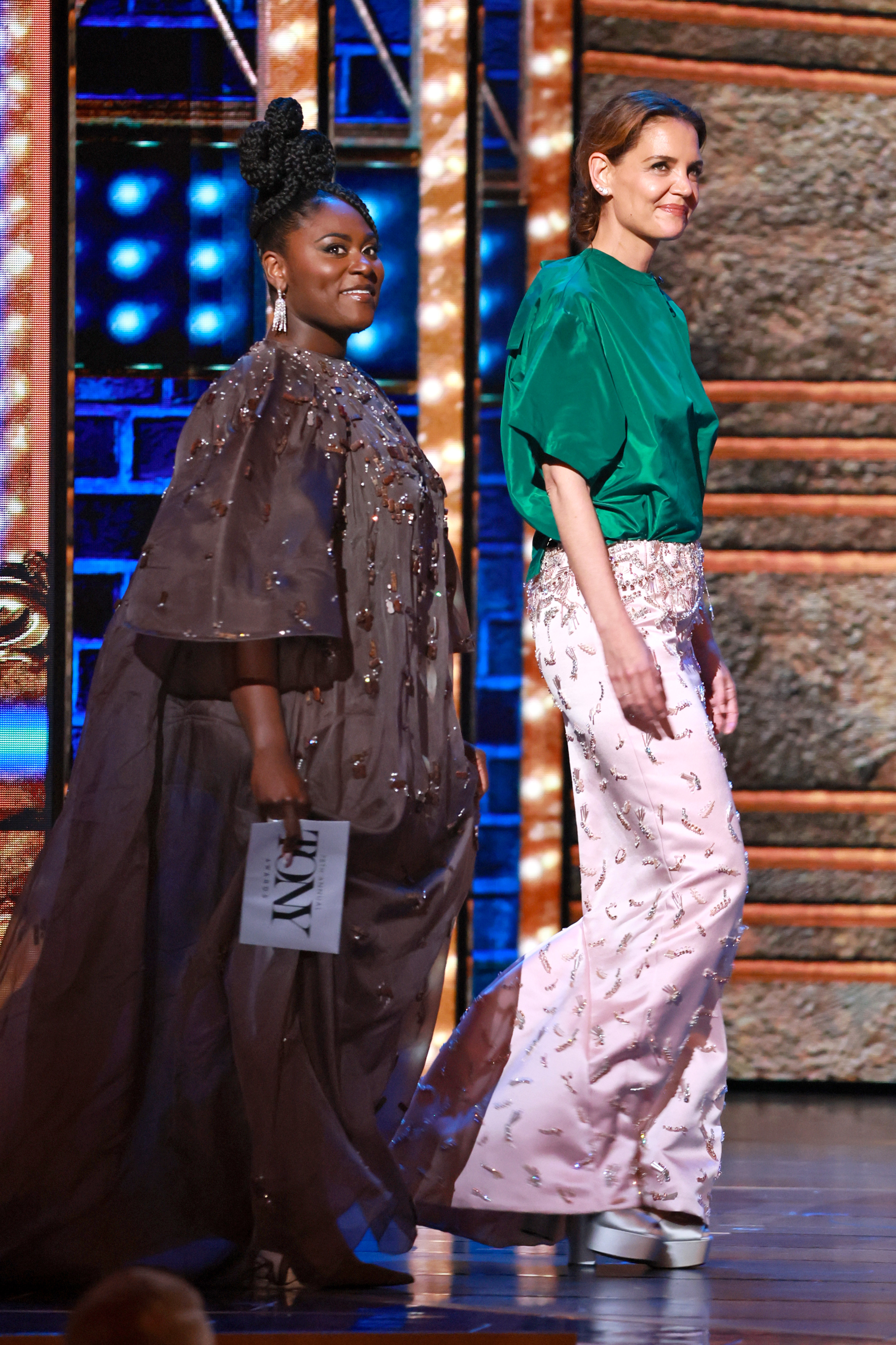 Katie Holmes walks onstage alongside Danielle Brooks during the 78th Annual Tony Awards, presenting with poise and a smile in a bold green top and blush pink skirt at Radio City Music Hall on June 8, 2025.