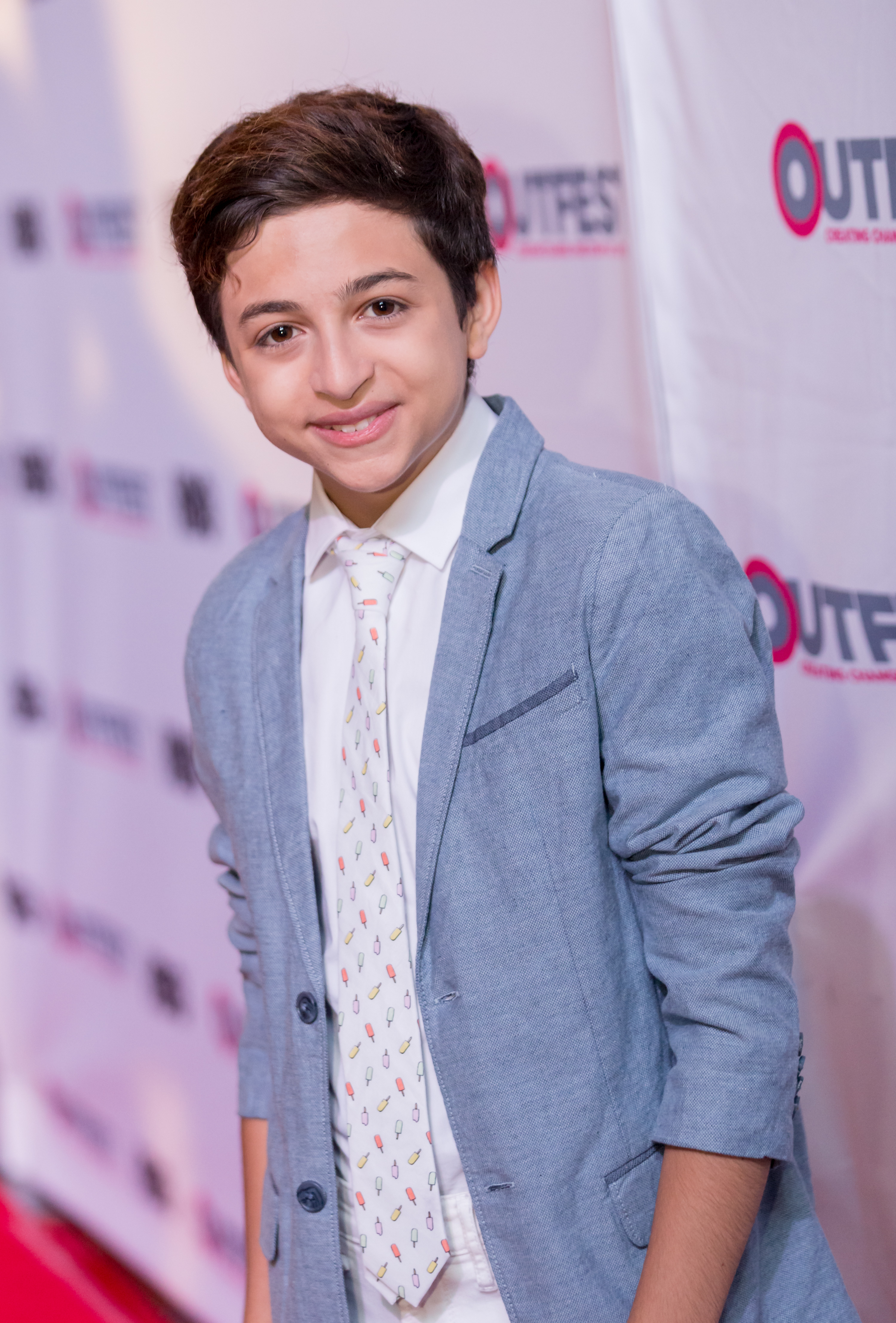 J.J. Totah attends the closing-night gala of Other People at Outfest Los Angeles in Los Angeles, California, wearing a light blue blazer, a white shirt, and a patterned tie. | Source: Getty Images