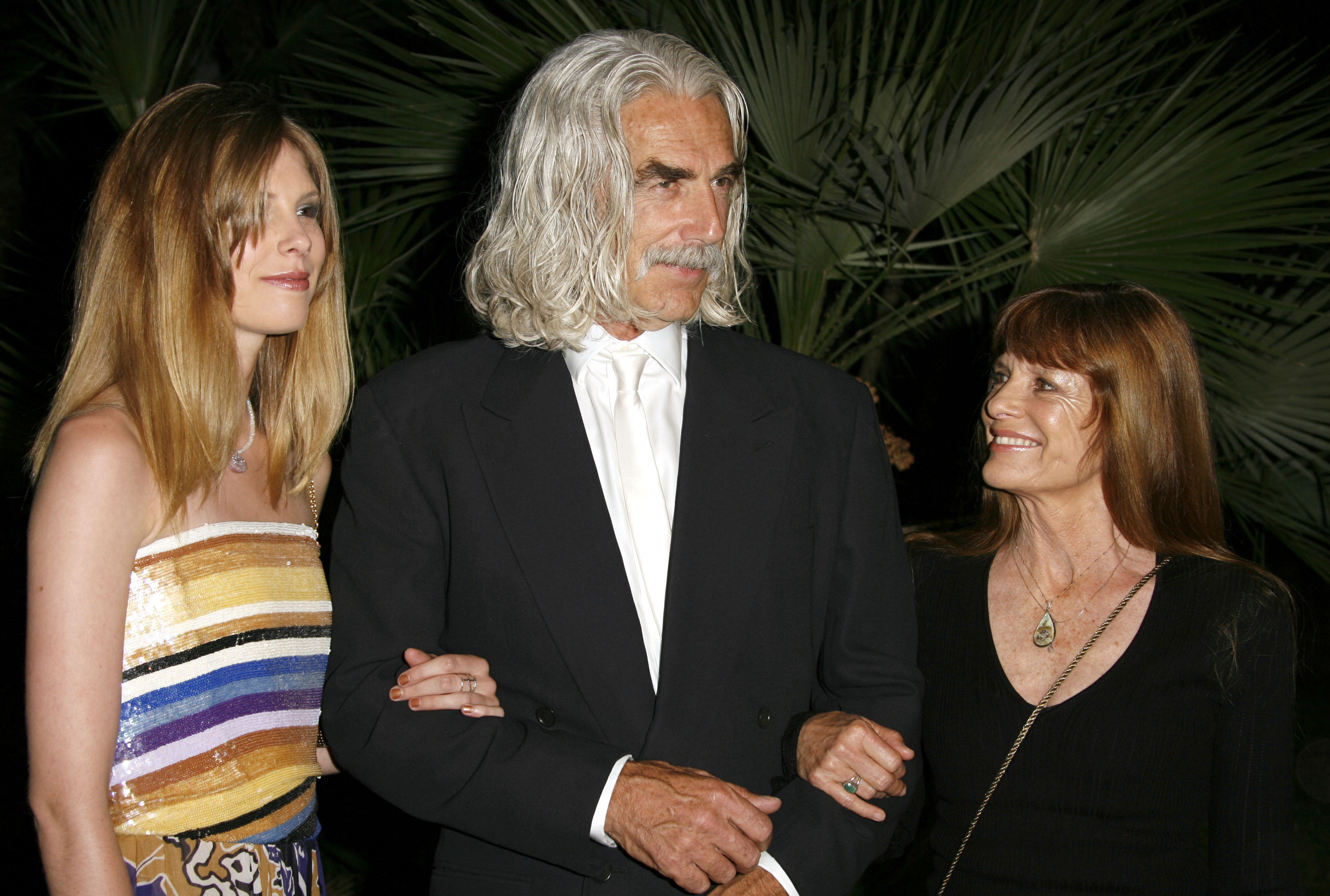 Sam Elliott walked arm-in-arm with his wife, Katharine Ross, and their daughter, Cleo Rose Elliott, at the New Line 40th Anniversary "The Golden Compass" party during the 2007 Cannes Film Festival in Cannes, France. Looking striking with his long silver hair and a sharp black suit paired with a crisp white tie, Sam shared a warm look with Katharine, who smiled brightly in an elegant black ensemble, while Cleo stood beautifully by his side in a vibrant, sequined strapless top featuring colorful horizontal stripes. | Source: Getty Images