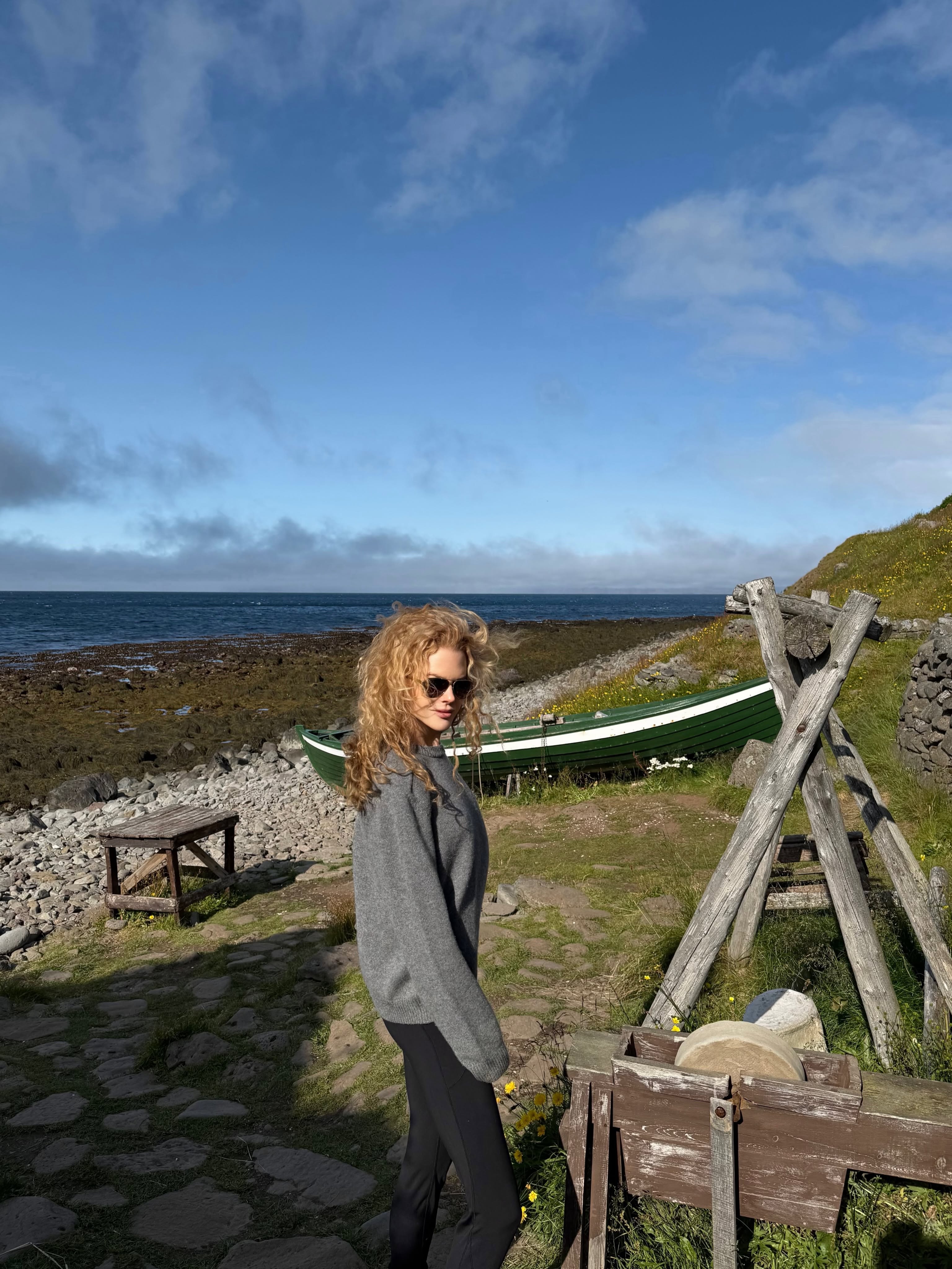 Soaking in the rugged Icelandic landscape, Nicole poses in sunglasses and a relaxed sweater along the stony shoreline. Her voluminous '90s-style ringlets took center stage against the dramatic coastal backdrop. | Source: Instagram/nicolekidman