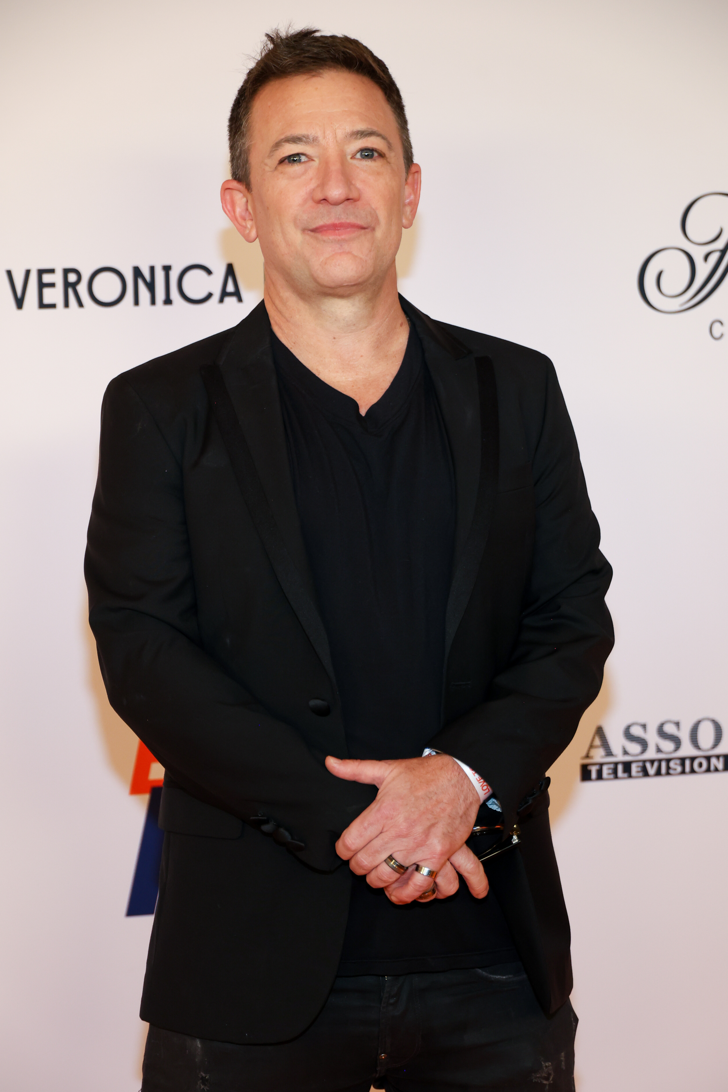 David Faustino smiled warmly as he posed on the red carpet while attending the 32nd Annual Race To Erase MS Gala on May 16, 2025, at Fairmont Century Plaza in Los Angeles, California. The actor opted for a sleek, all-black ensemble featuring a tailored blazer layered over a casual V-neck tee and matching trousers, hands loosely clasped in front of him as he supported the charitable cause. | Source: Getty Images