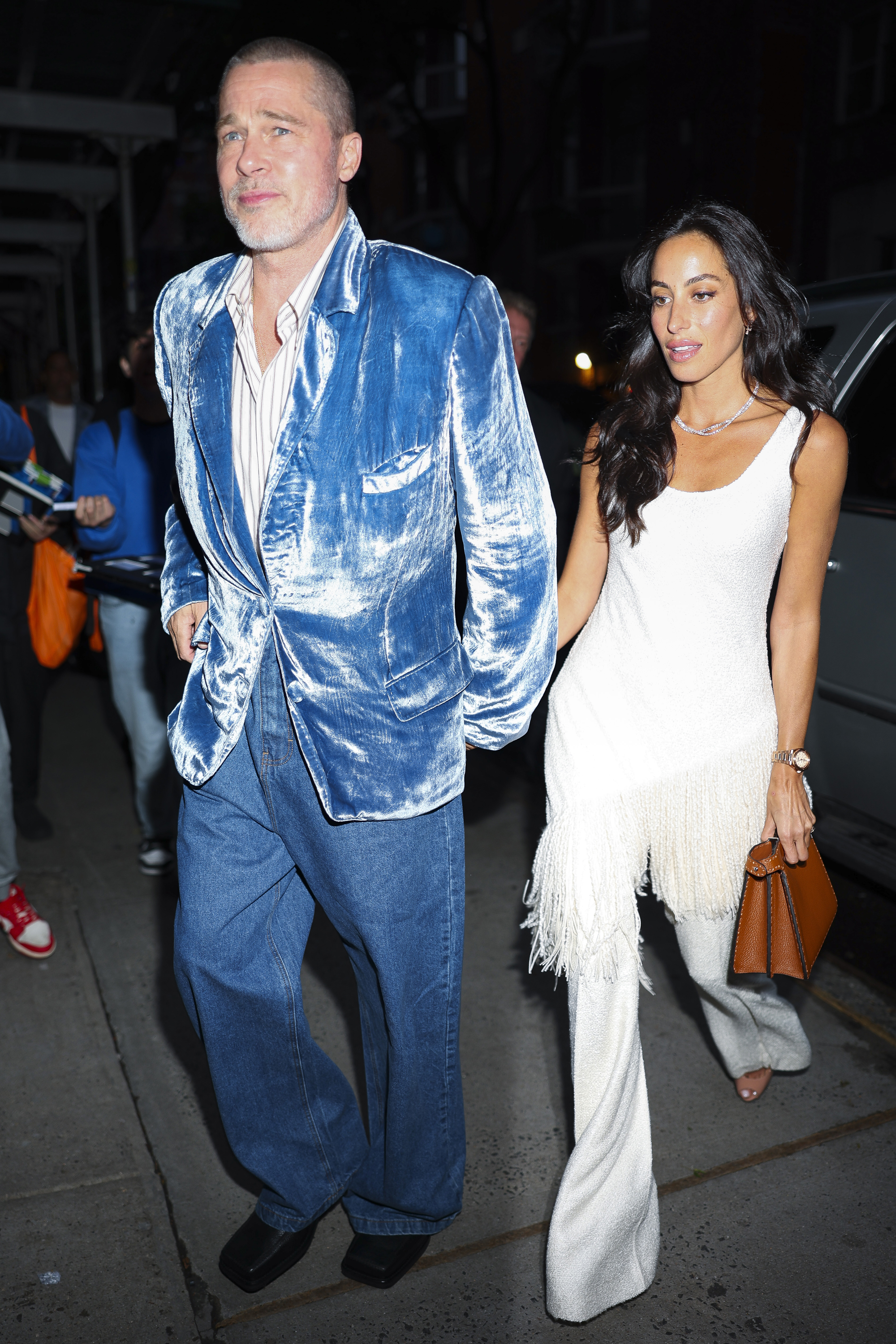 Pitt made the bolder color choice on another night out, stepping out in a glossy blue jacket and relaxed trousers. Beside him, de Ramon kept things lighter in a white sleeveless look with fringe detailing and a brown handbag.