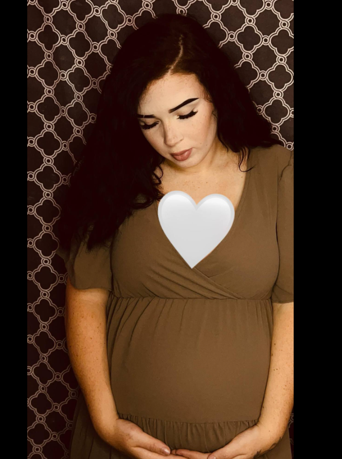 Keziah Luker stands against a patterned backdrop, gently cradling her baby bump with both hands, from a post dated July 2, 2024. | Source: Facebook/Keziah Luker