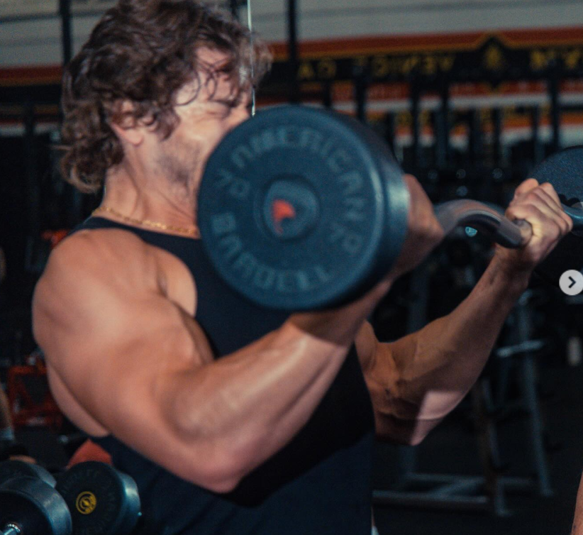 With intensity building, Joseph Baena powers through the curl, arms fully engaged as the weight rises, capturing the peak of effort and control in the lift. | Source: Instagram/joebaena
