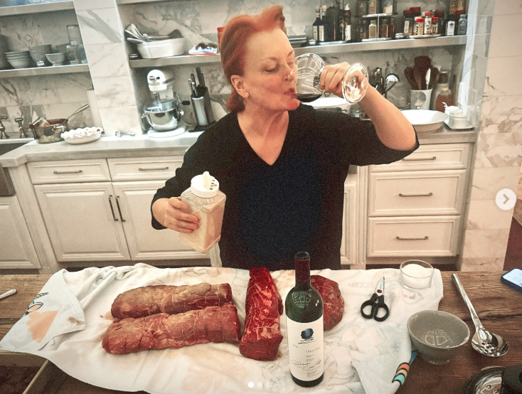 Wynonna raises a glass while standing behind a counter covered with food ingredients and kitchen tools. The casual moment shows her participating in the preparations rather than simply posing beside a finished meal. | Source: Instagram/wynonnajudd